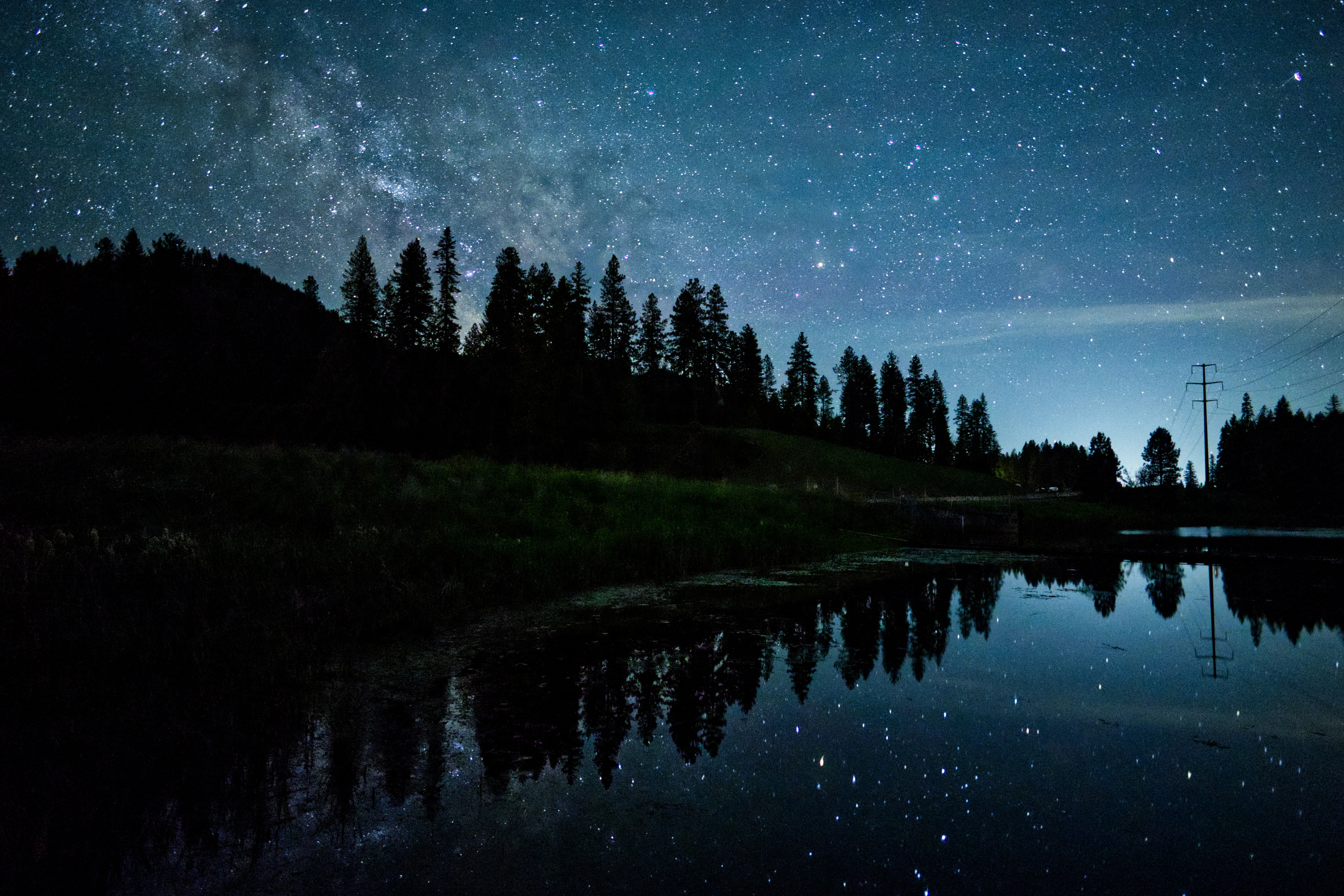 the night sky is reflected in the still water of a lake