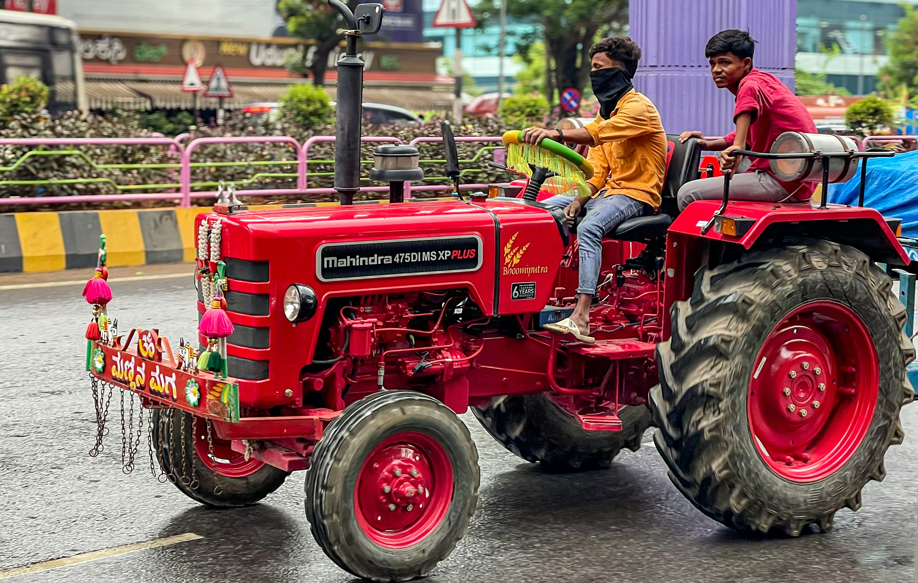 two men are riding on a red tractor