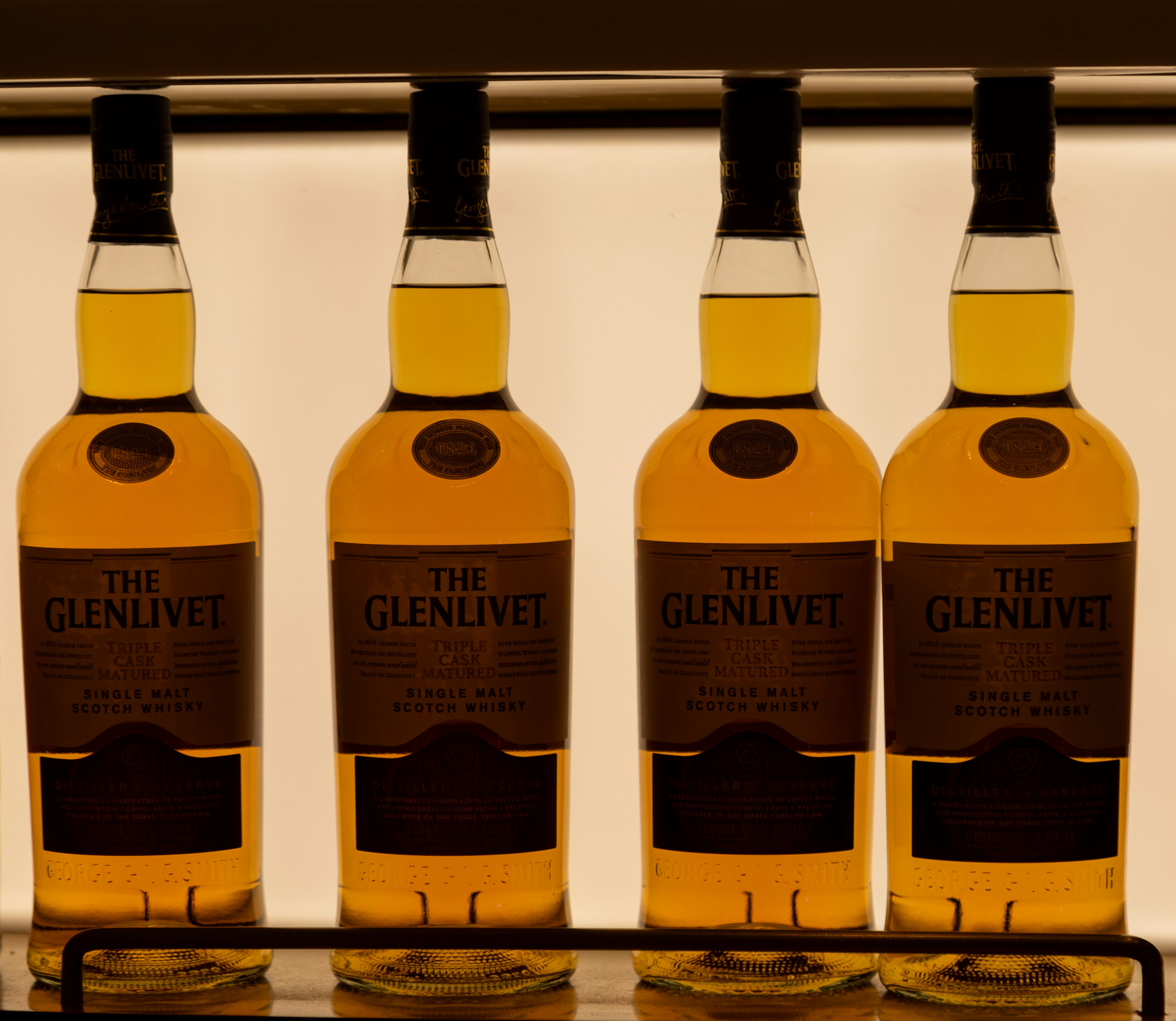 three bottles of whisky are lined up on a shelf