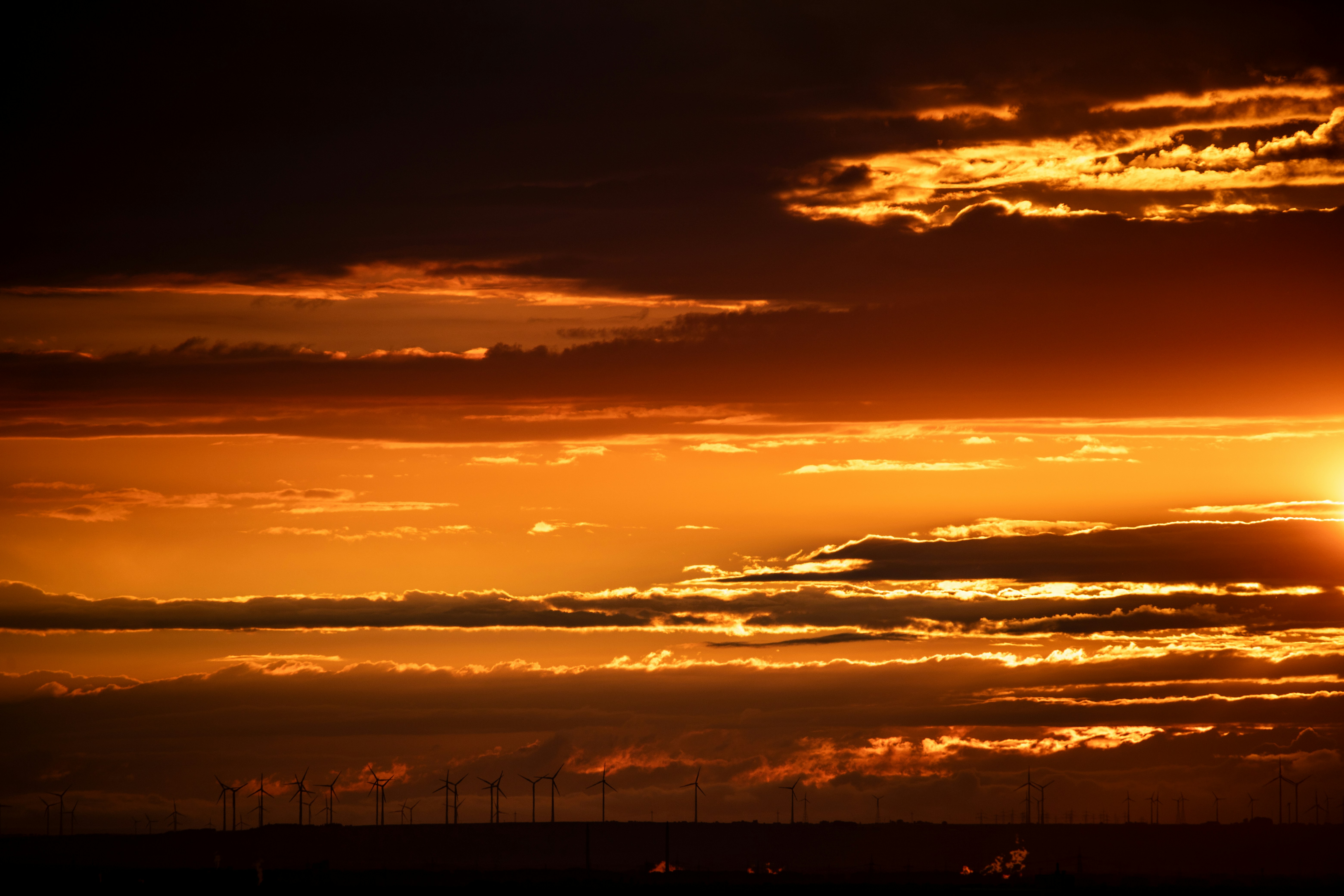 the sun is setting over a field of wind mills