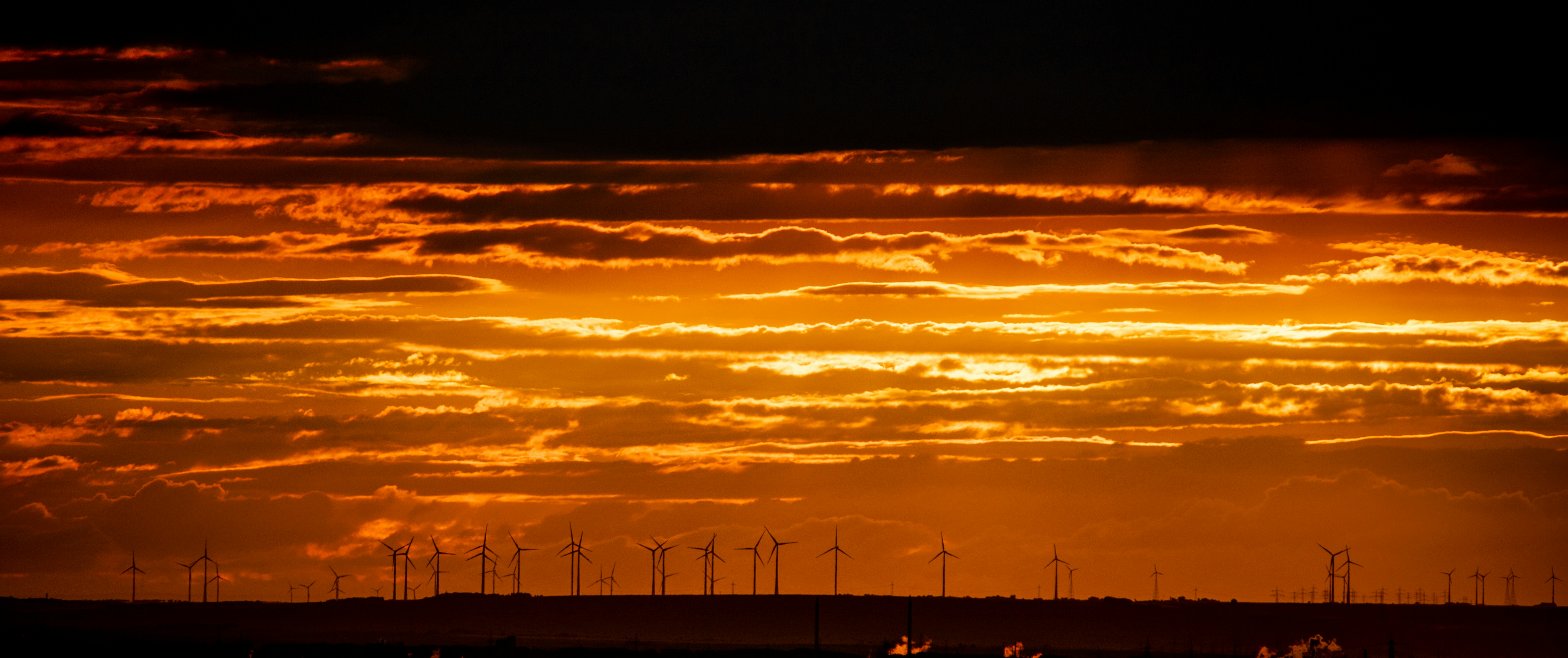 the sun is setting over a field of windmills