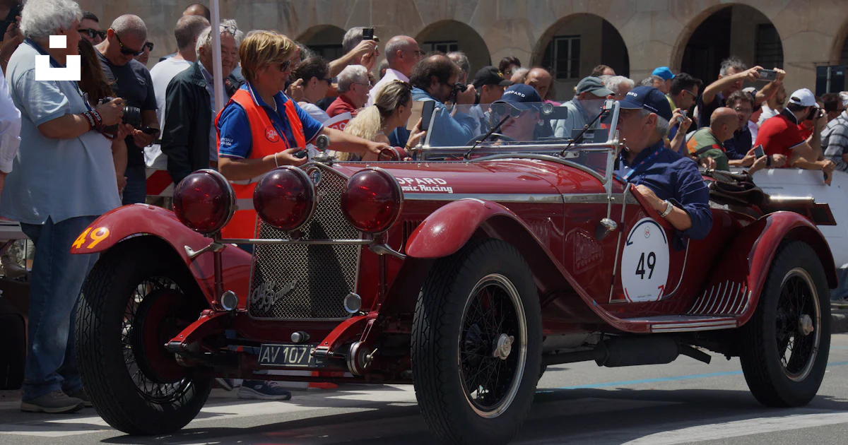 A red car with a number on it driving down a street photo – Free Genova ...