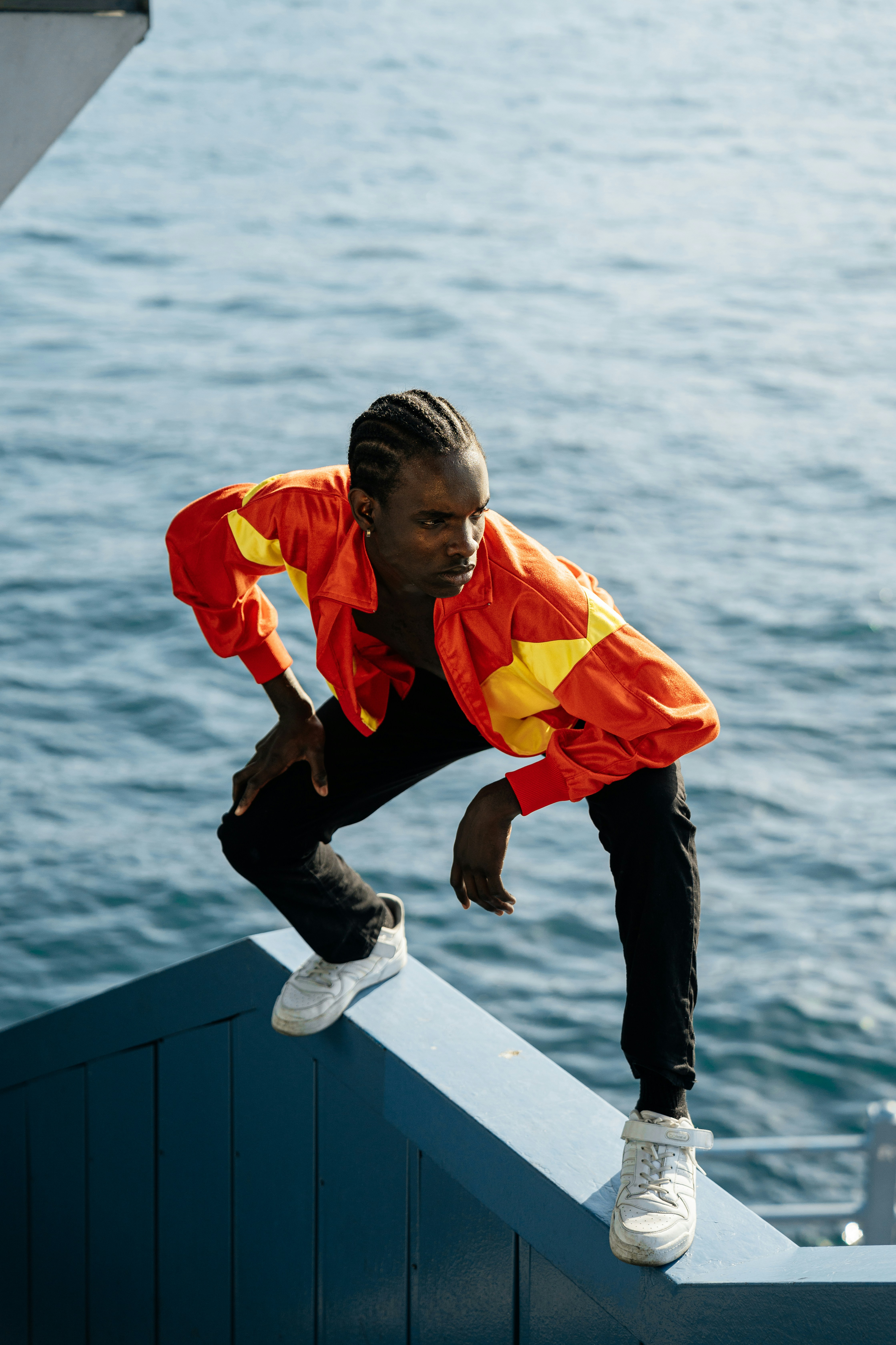 a man in an orange and yellow jacket leaning on a railing
