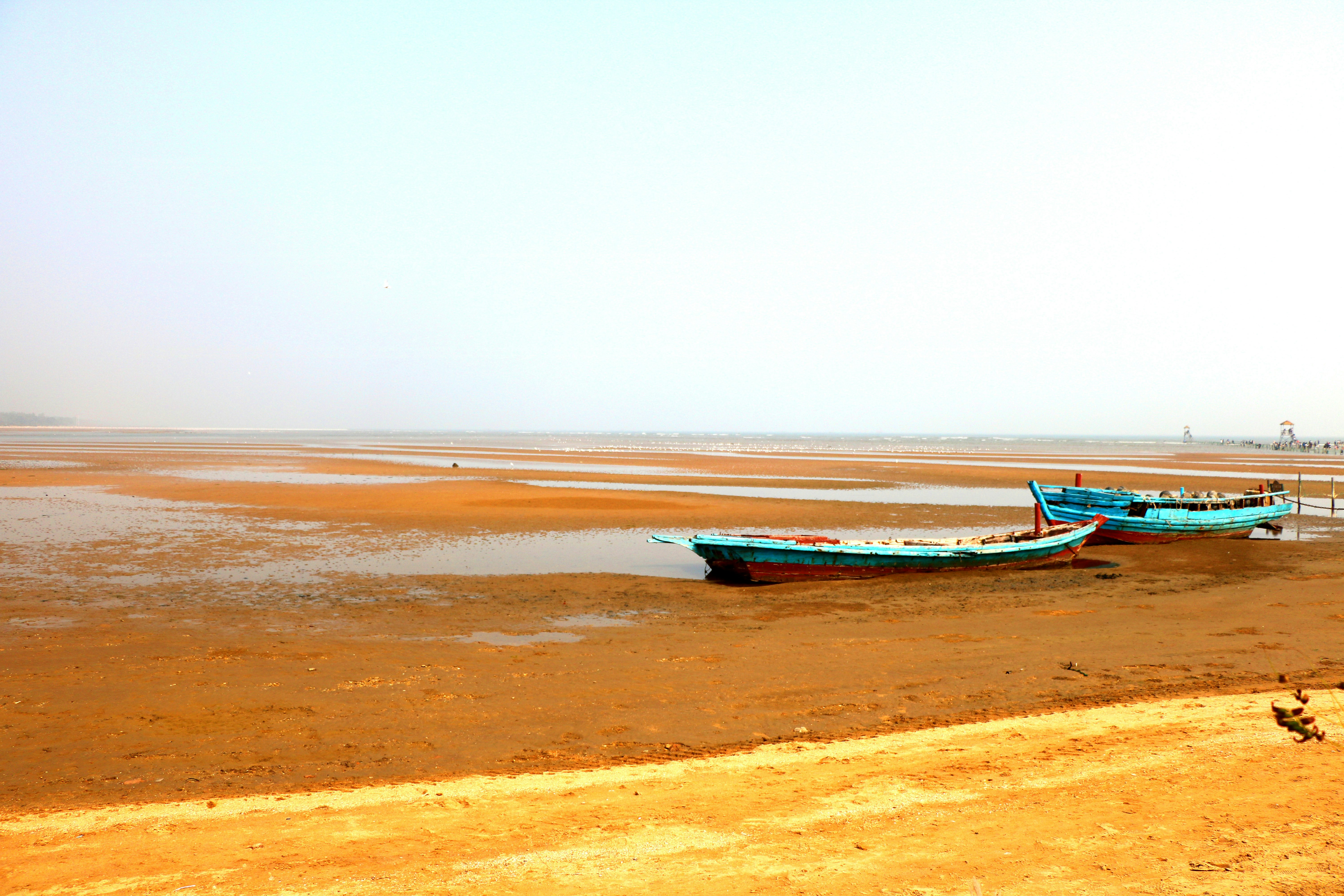 a couple of boats sitting on top of a sandy beach