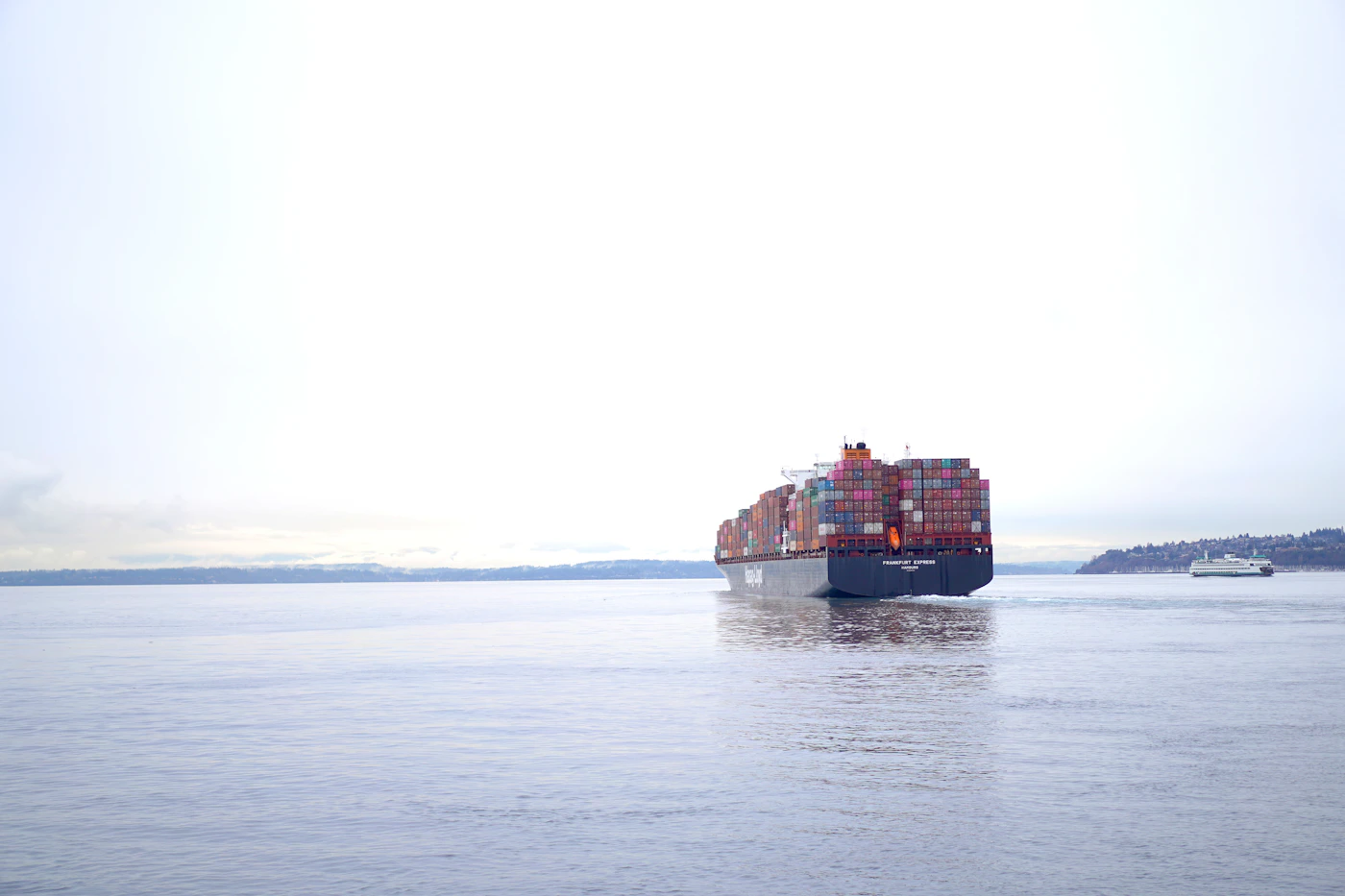 Cargo ship sailing across open blue water under a clear sky, representing a death that occurred on the high seas beyond three nautical miles