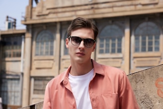 a man wearing sunglasses standing in front of a building