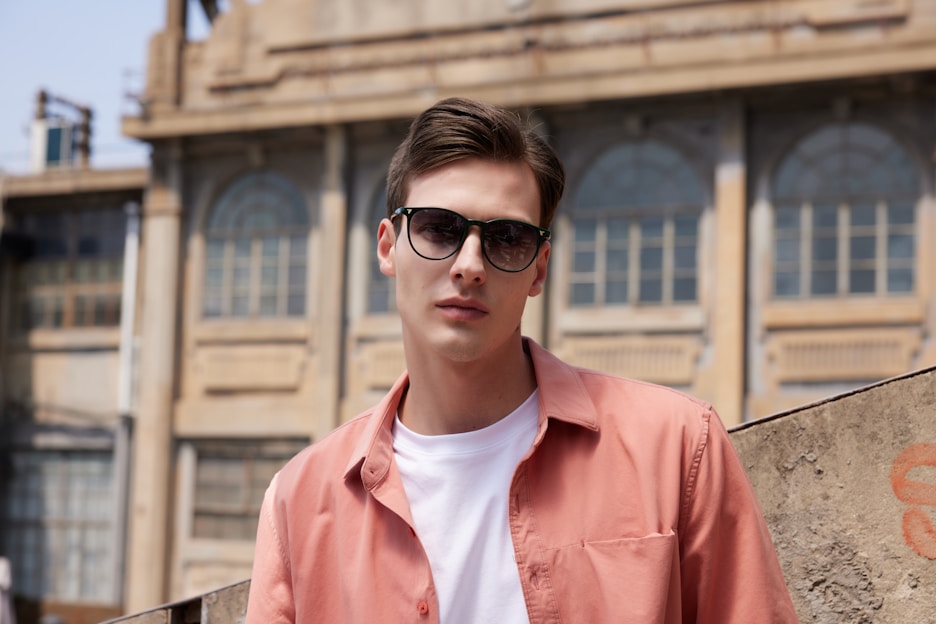 a man wearing sunglasses standing in front of a building