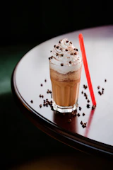 a drink with whipped cream and chocolate sprinkles on a table