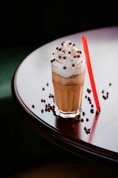 a drink with whipped cream and chocolate sprinkles on a table