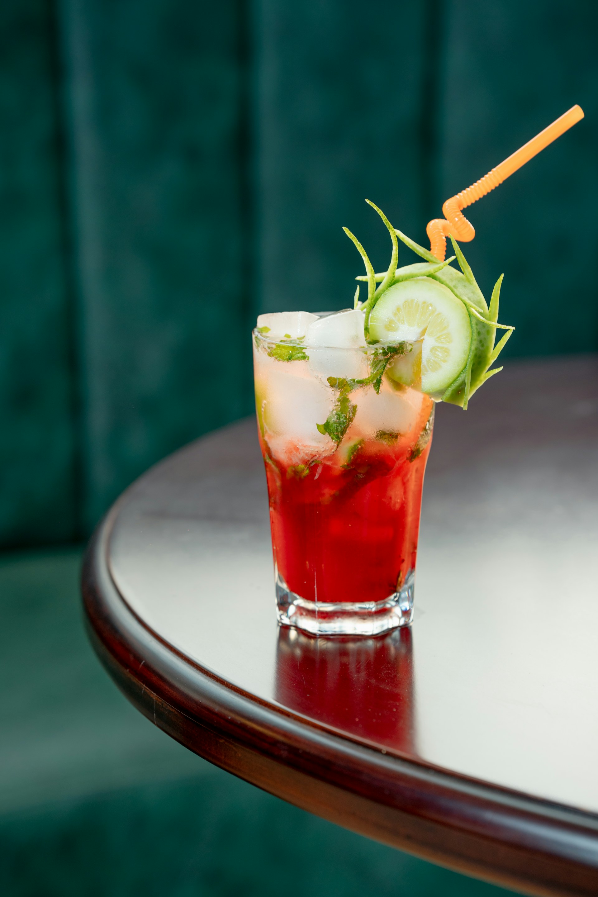 a drink with cucumber and mint garnish on a table