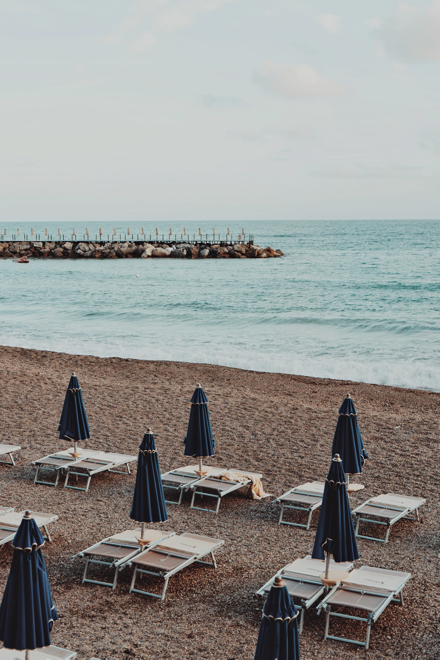 Beach chairs and umbrellas arranged beside the sea in a vertical coastal scene