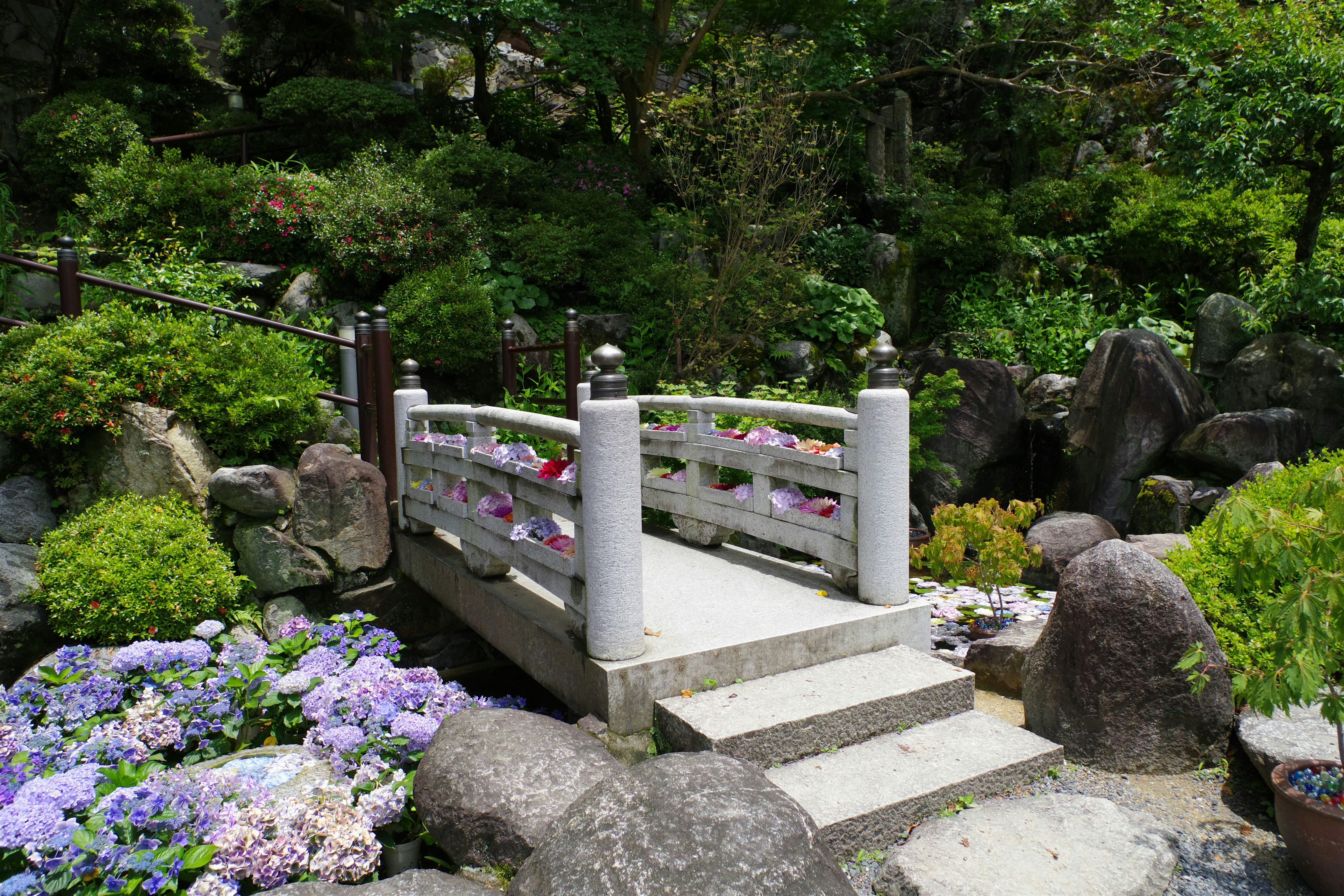 a stone bridge surrounded by flowers and rocks