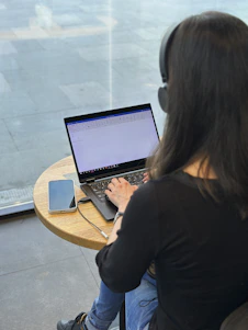 a woman sitting at a table using a laptop computer