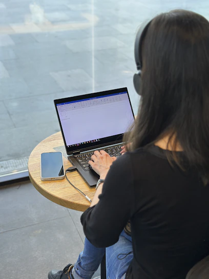 a woman sitting at a table using a laptop computer