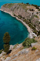a large body of water sitting next to a lush green hillside