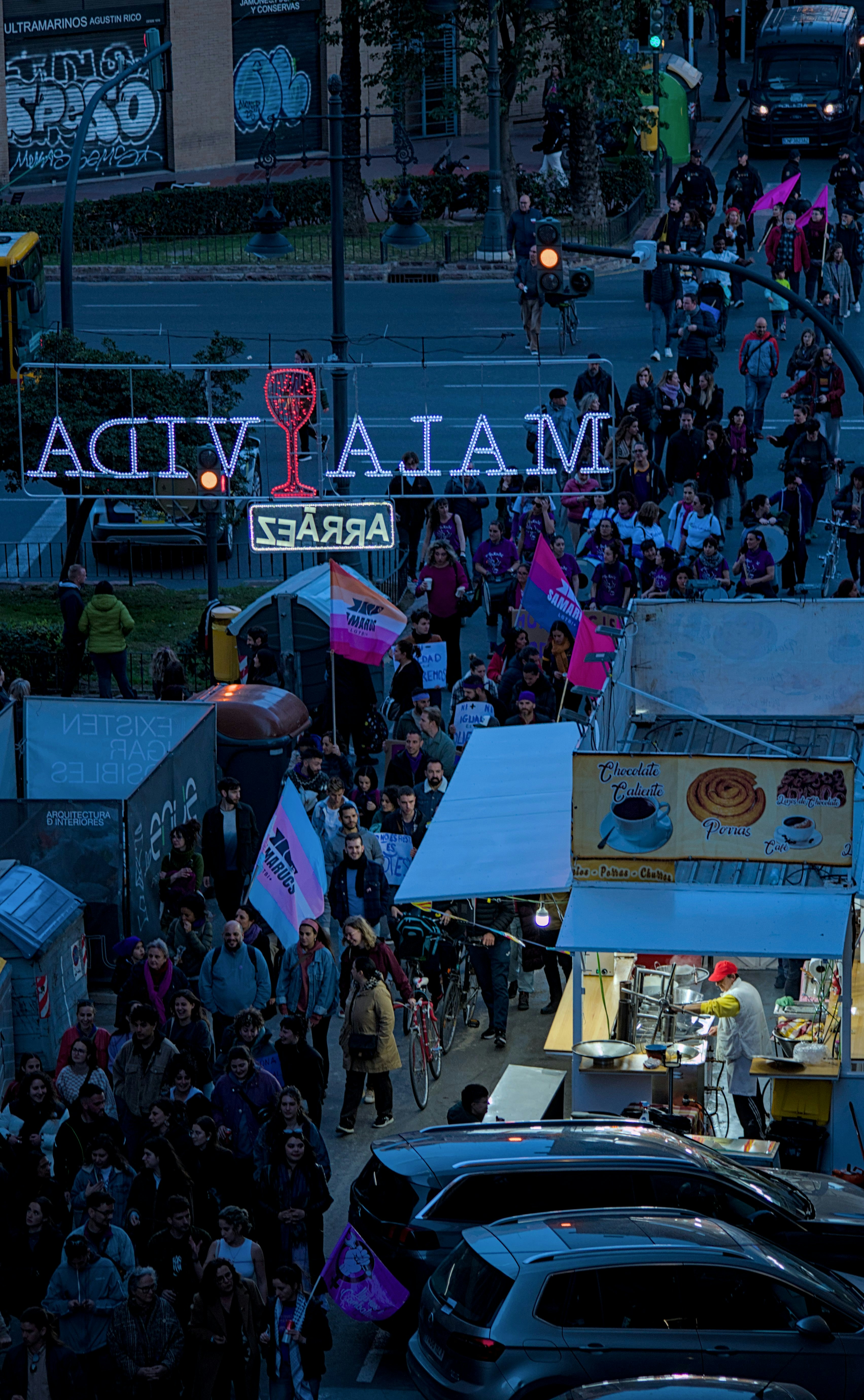 una multitud de personas caminando por una calle junto a un letrero de la calle