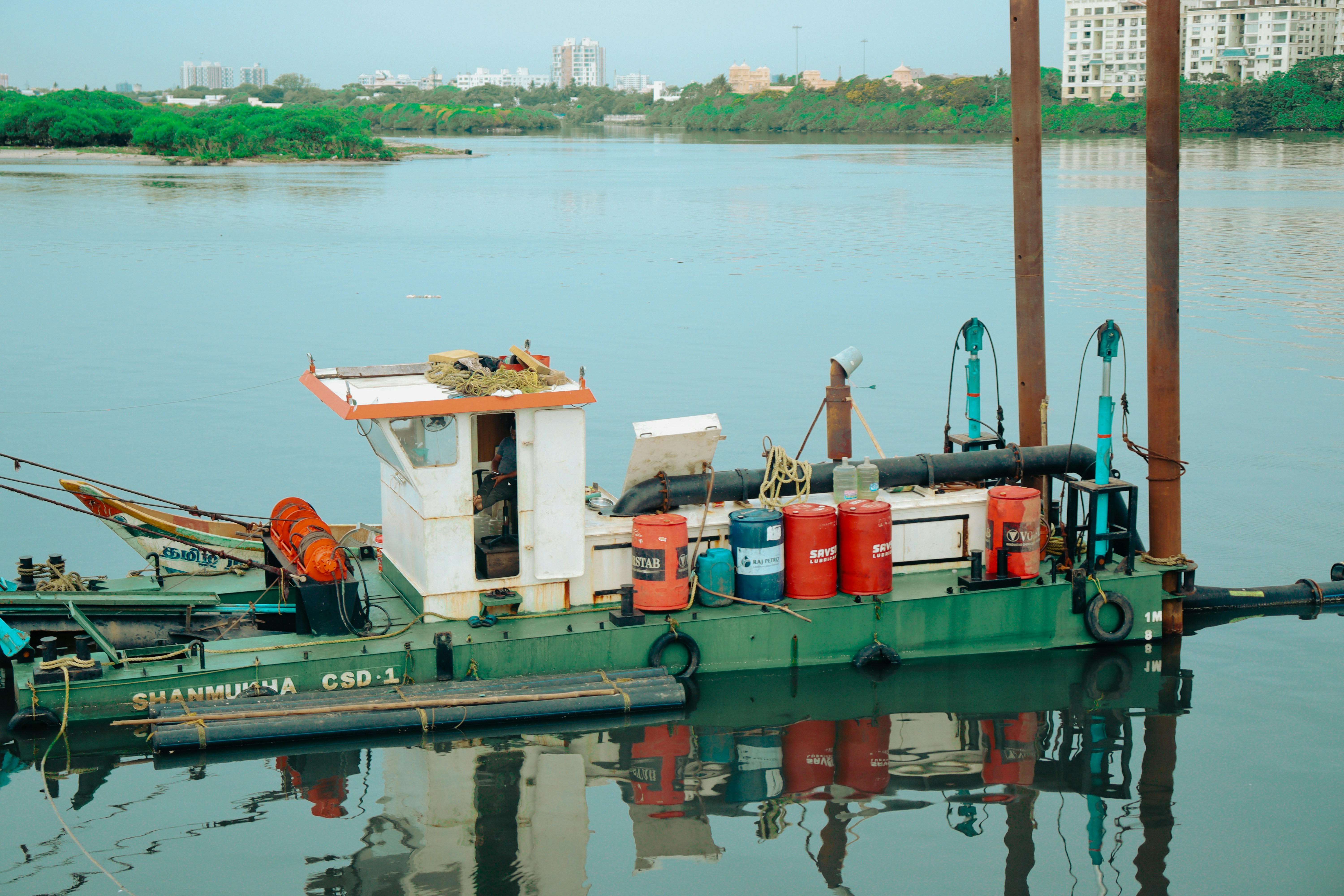 Una barcaza industrial de casco verde está amarrada en el agua.