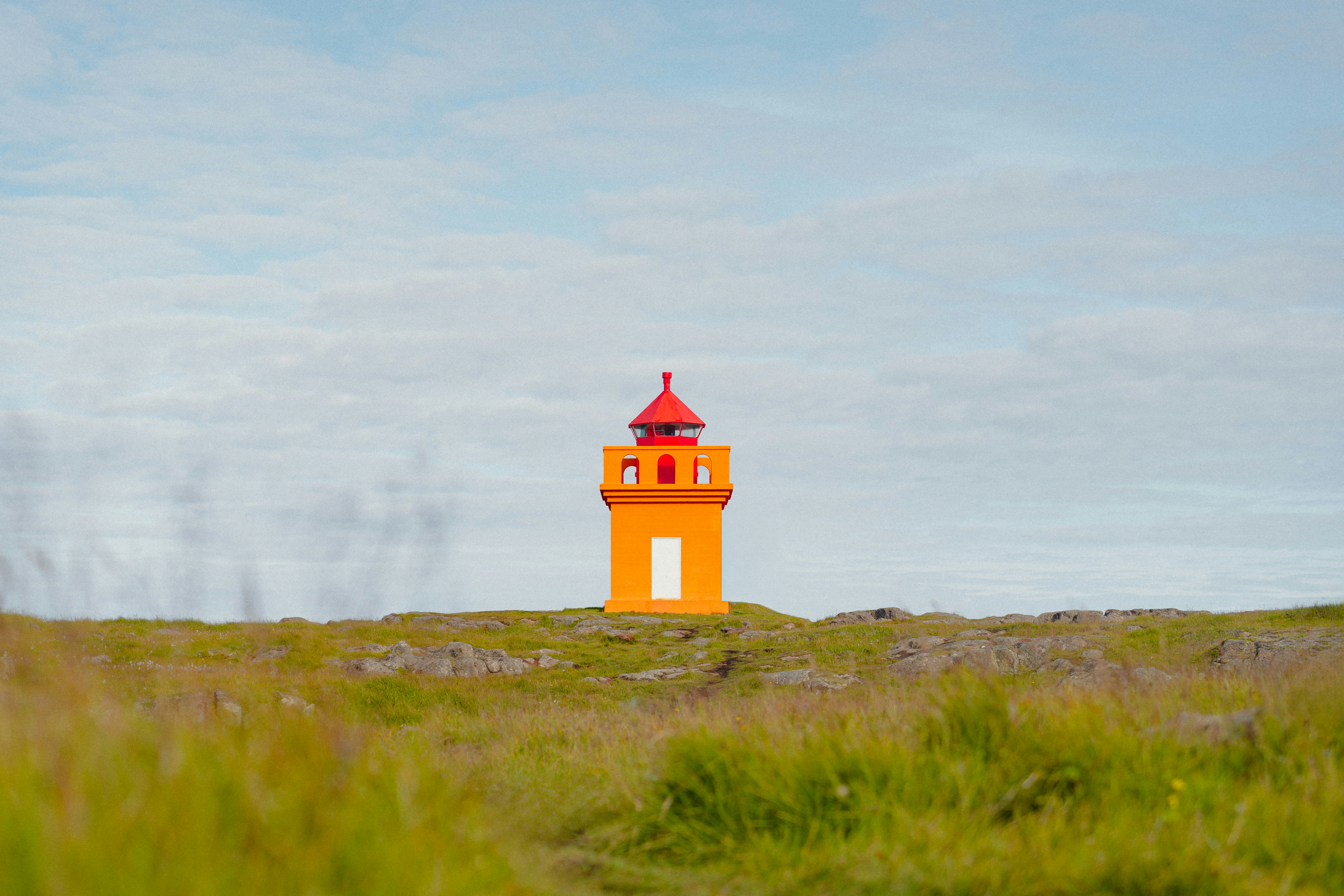 a red and white lighthouse on top of a hill