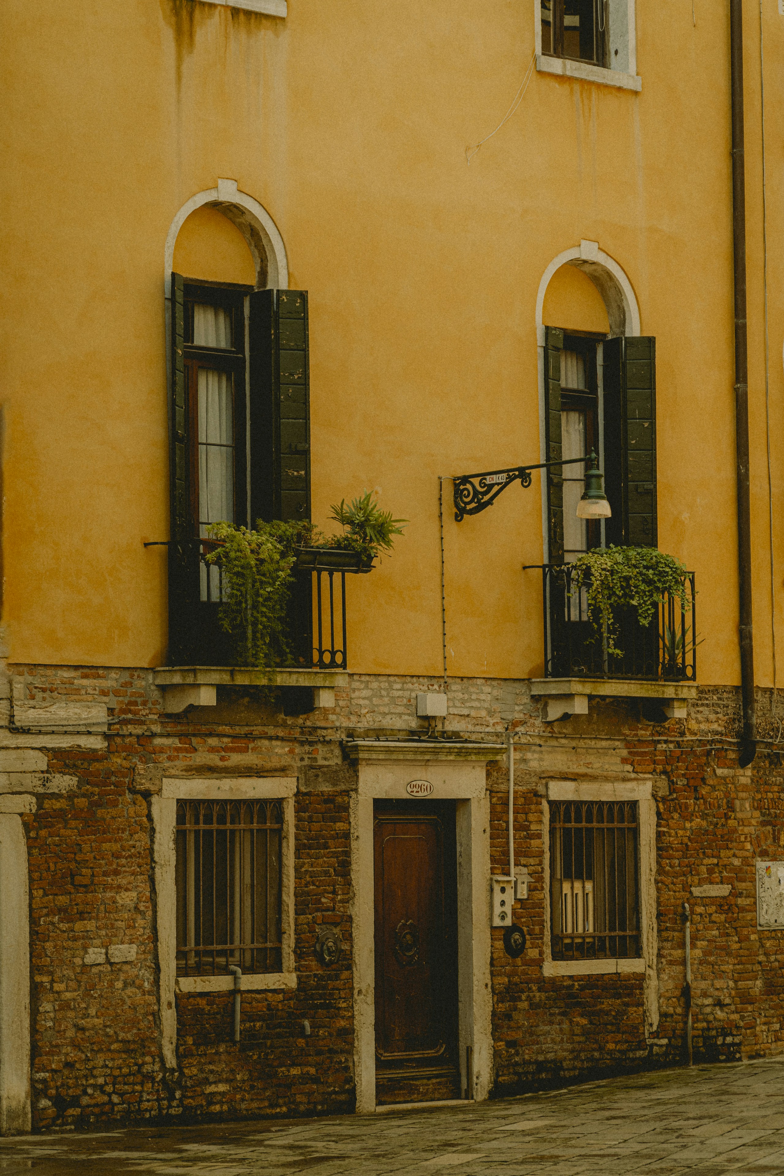 a yellow building with two balconies and two windows