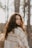 a woman with curly hair standing in the woods