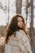 a woman with curly hair standing in the woods