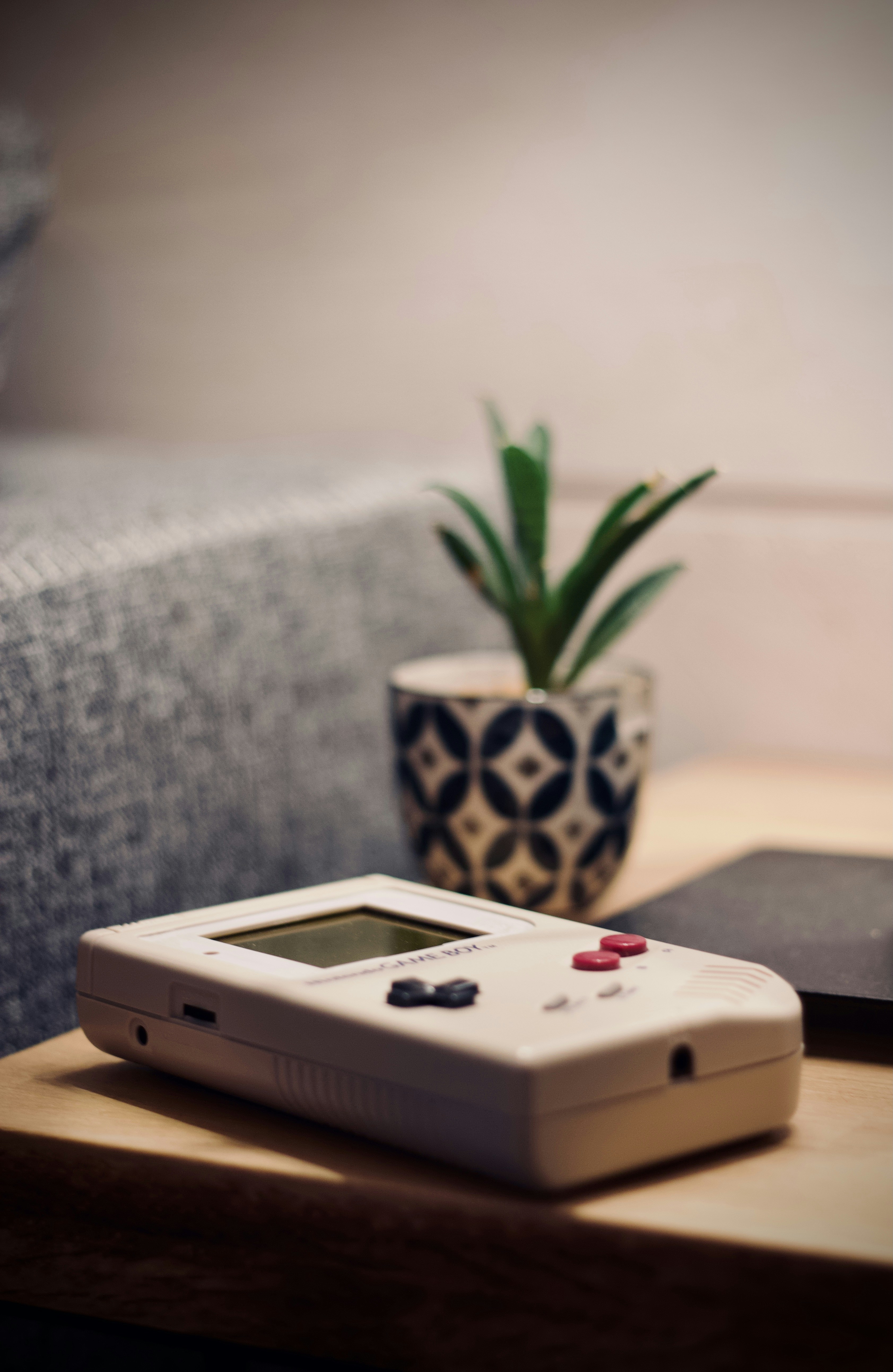 Vintage Nintendo handheld gaming device on dark wooden table with moody low-key lighting