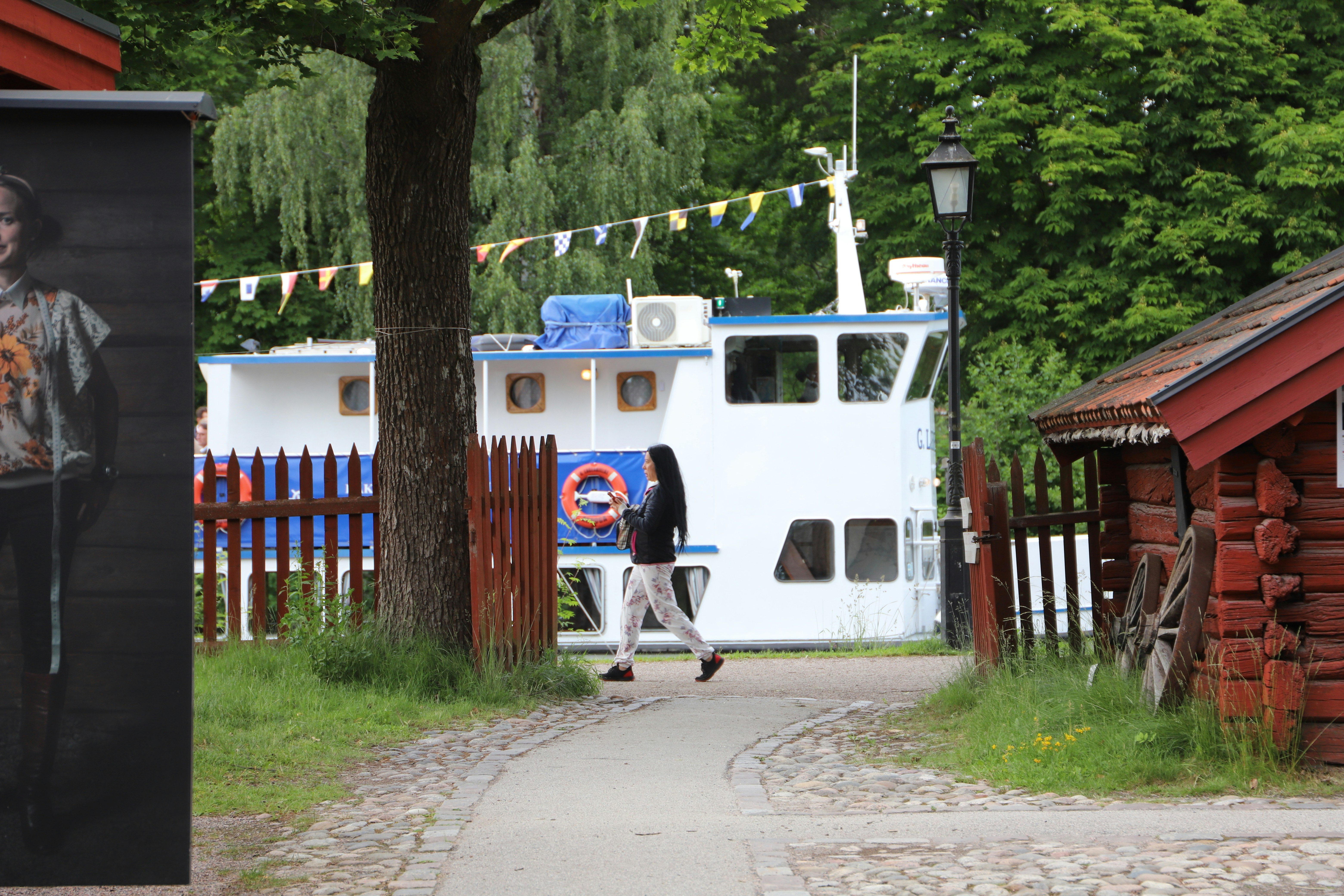 a man walking down a sidewalk next to a boat