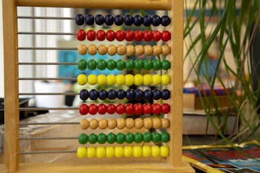 a wooden abacusk sitting on top of a table next to a plant