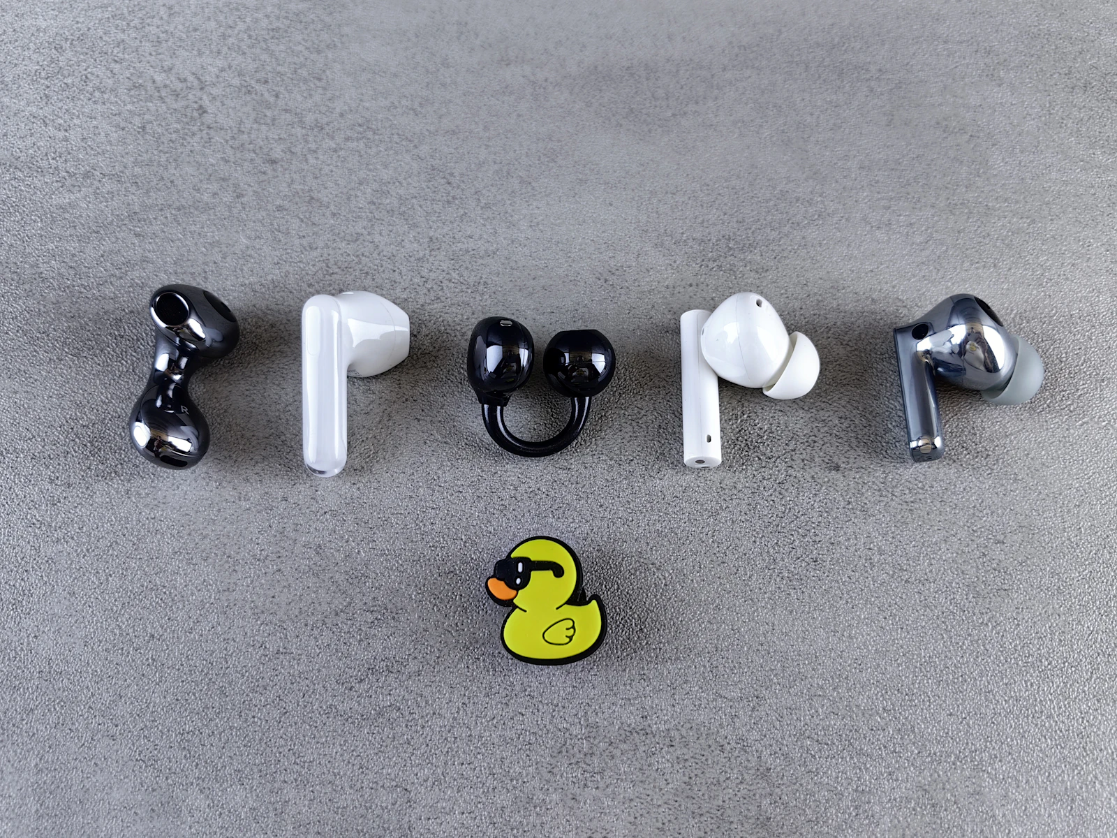Several pairs of wireless earbuds arranged side by side for comparison