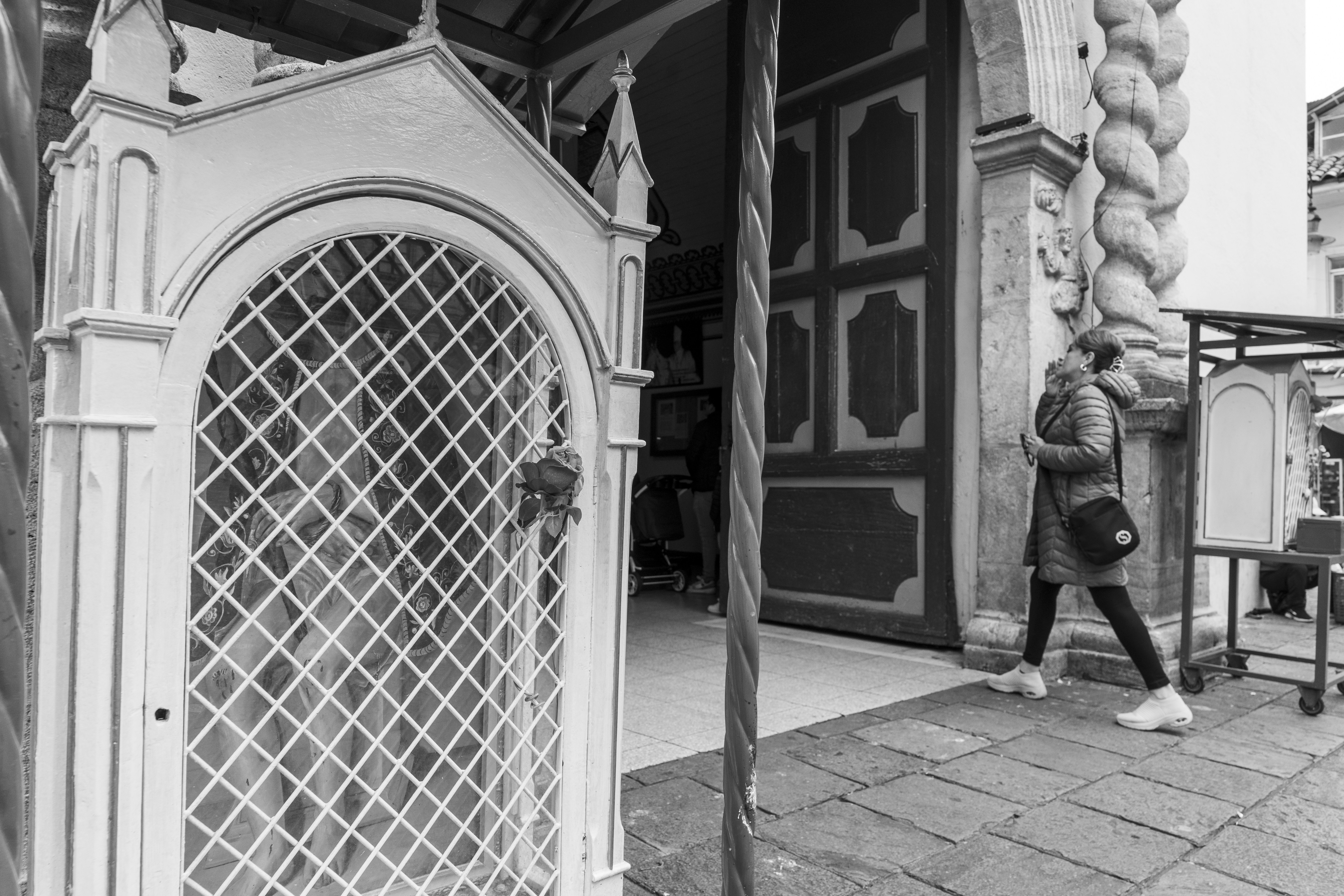 a black and white photo of a person walking past a building