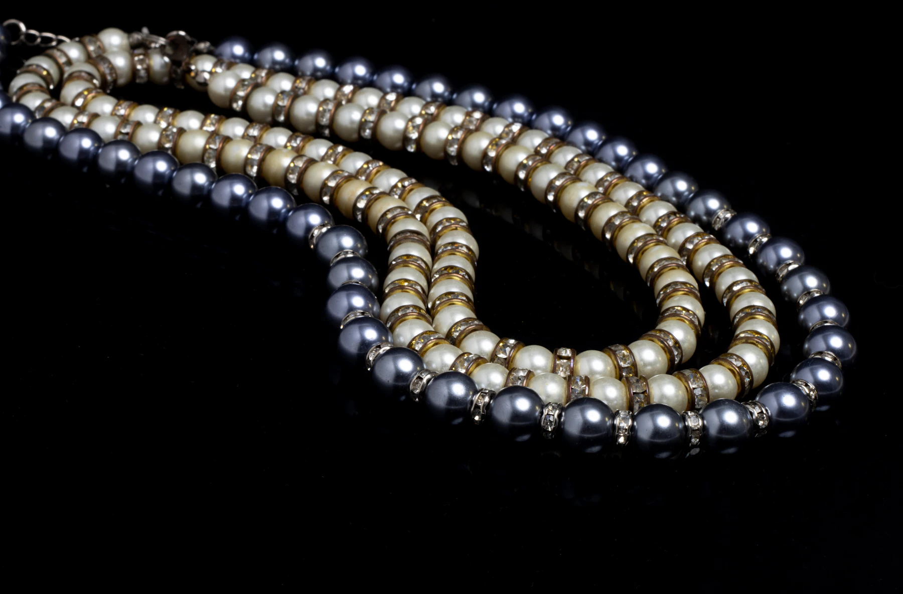 Grey and ivory pearl strands against a dark background, showing differences in colour and surface appearance