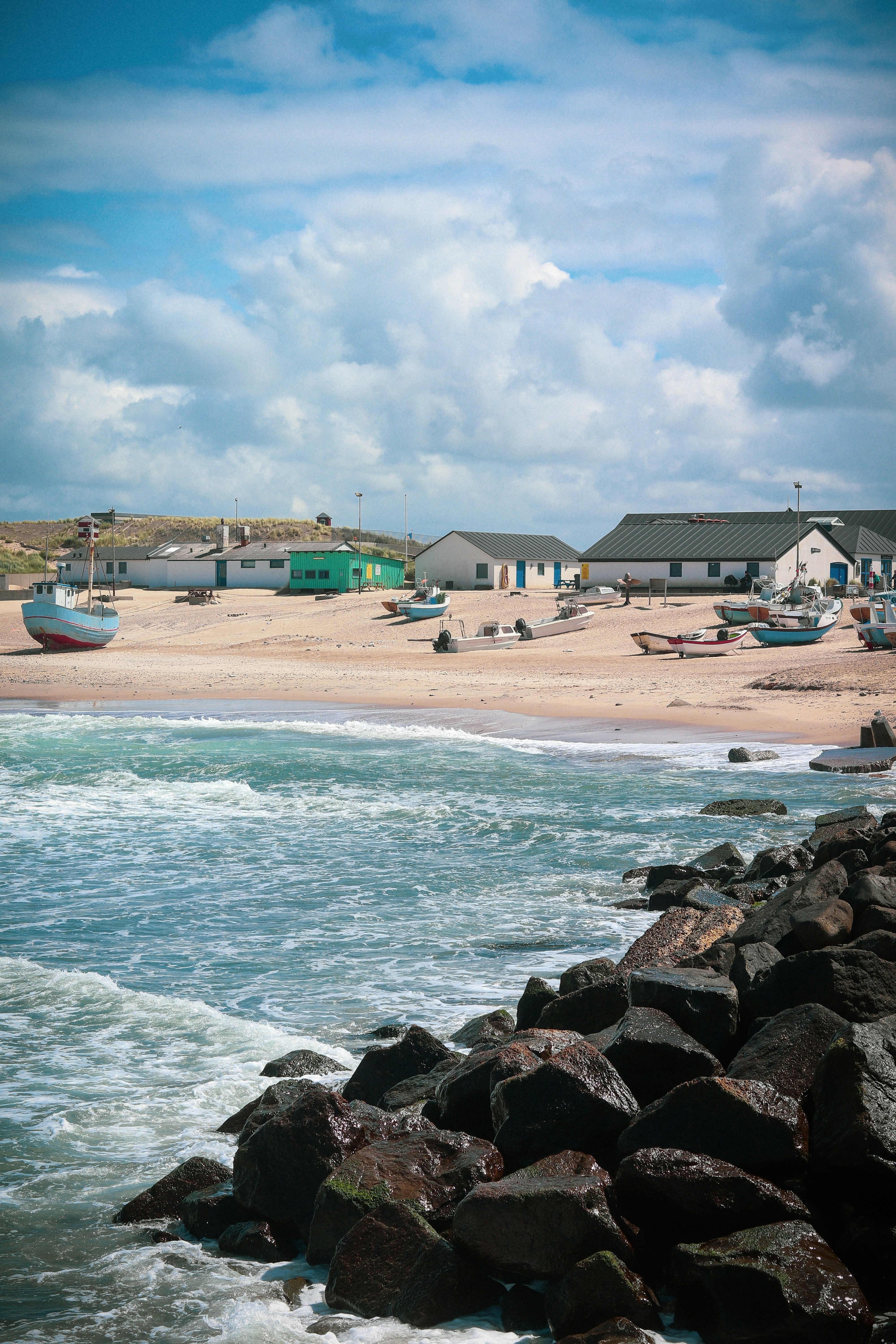 a sandy beach with houses and boats in the water