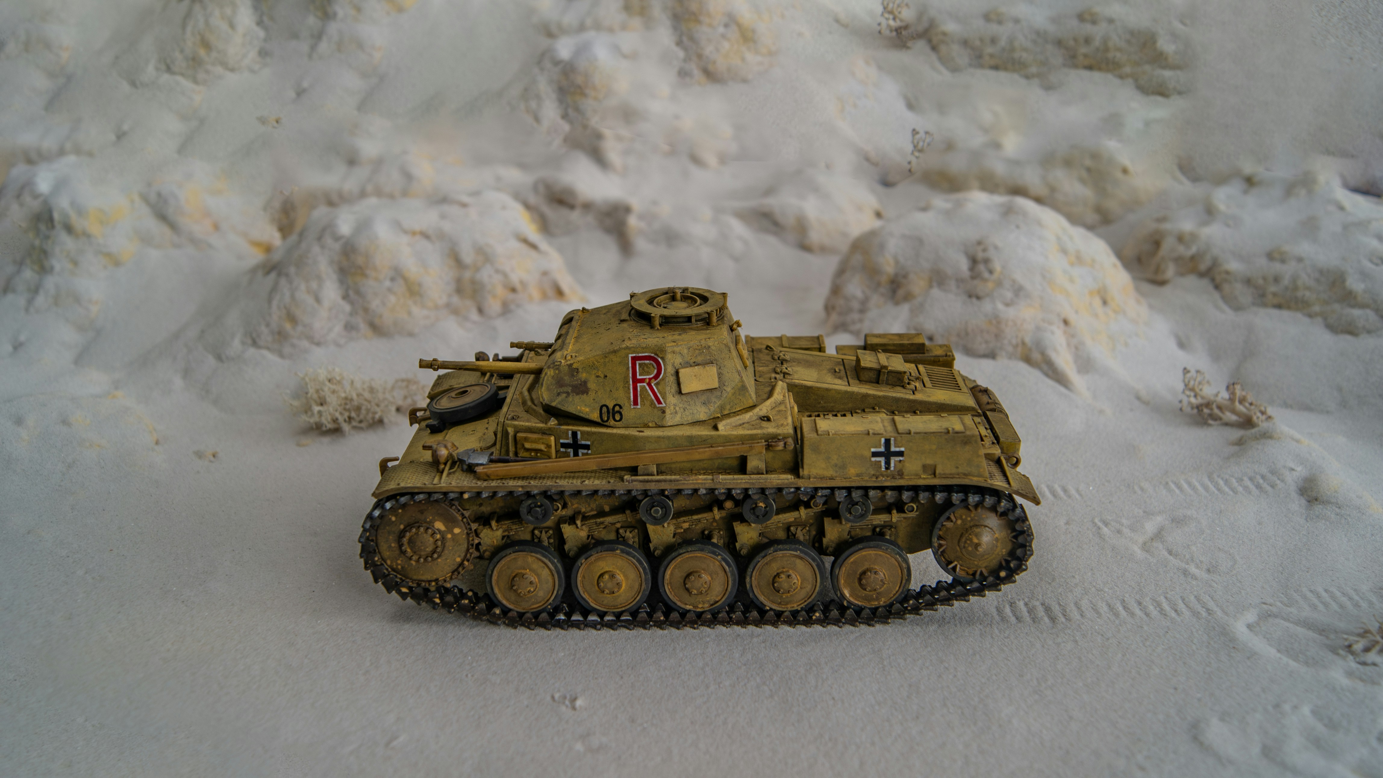 a toy army tank sitting in the snow