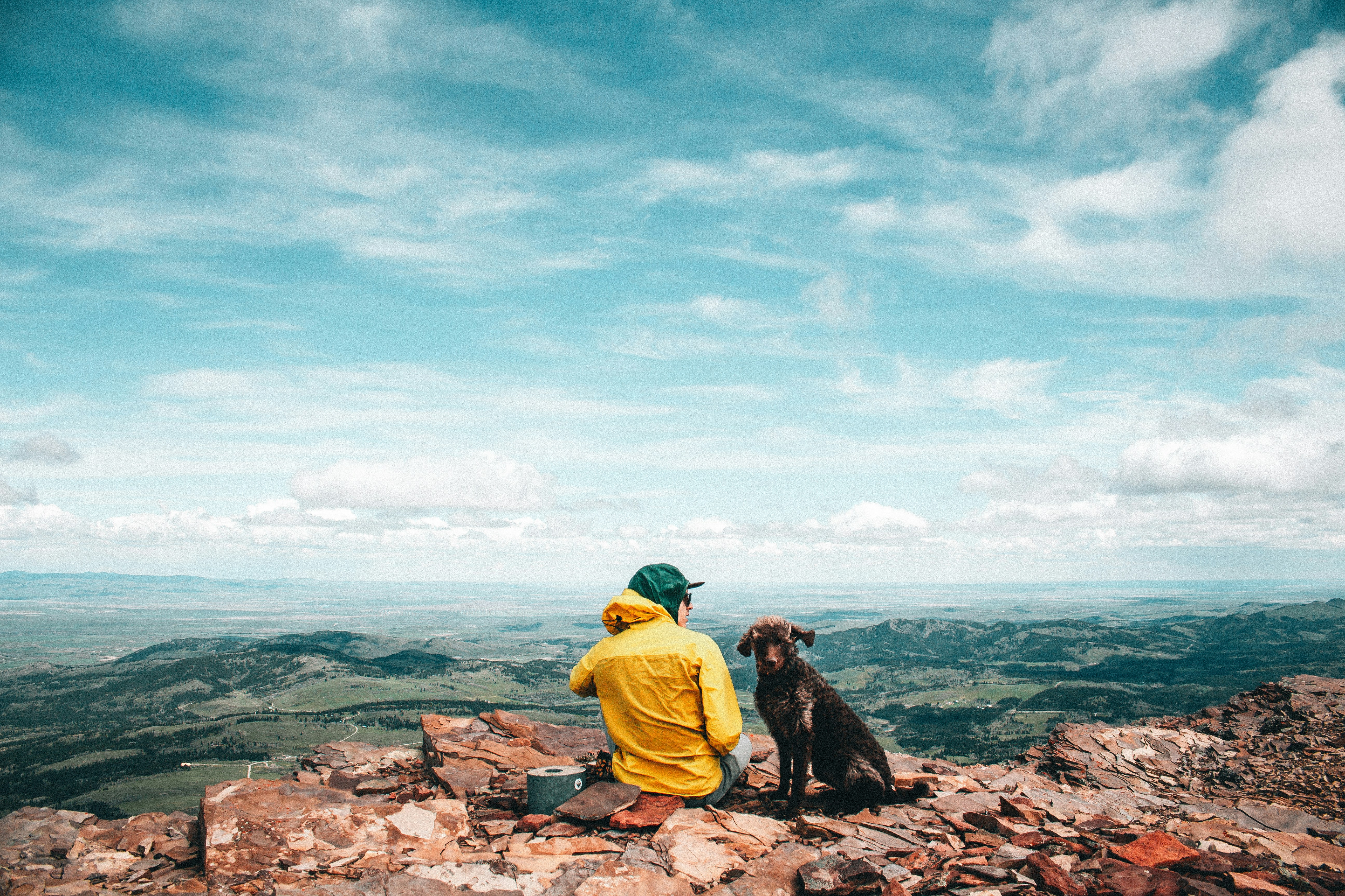 a man sitting on top of a mountain with a dog