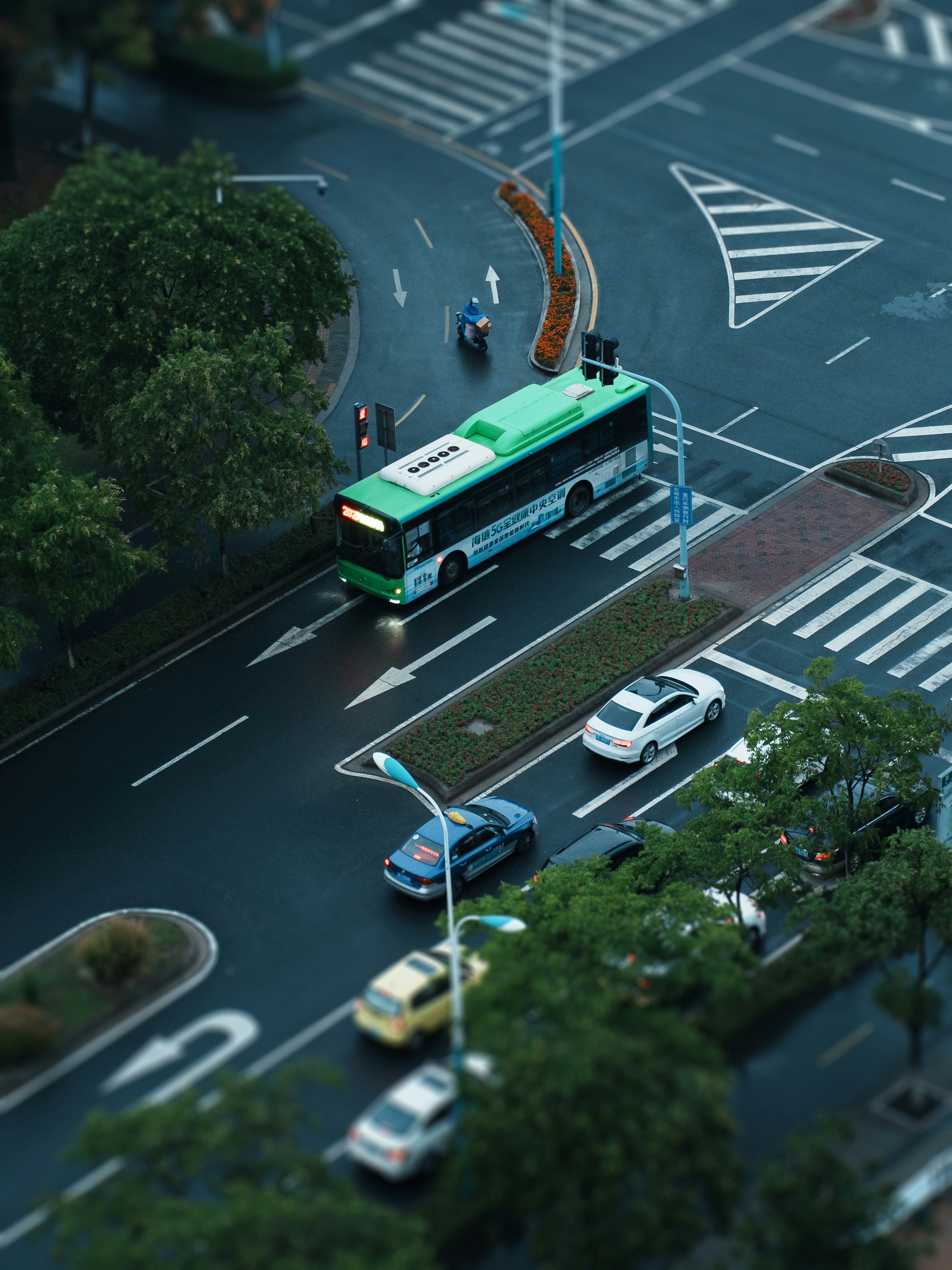 a green and white bus driving down a street