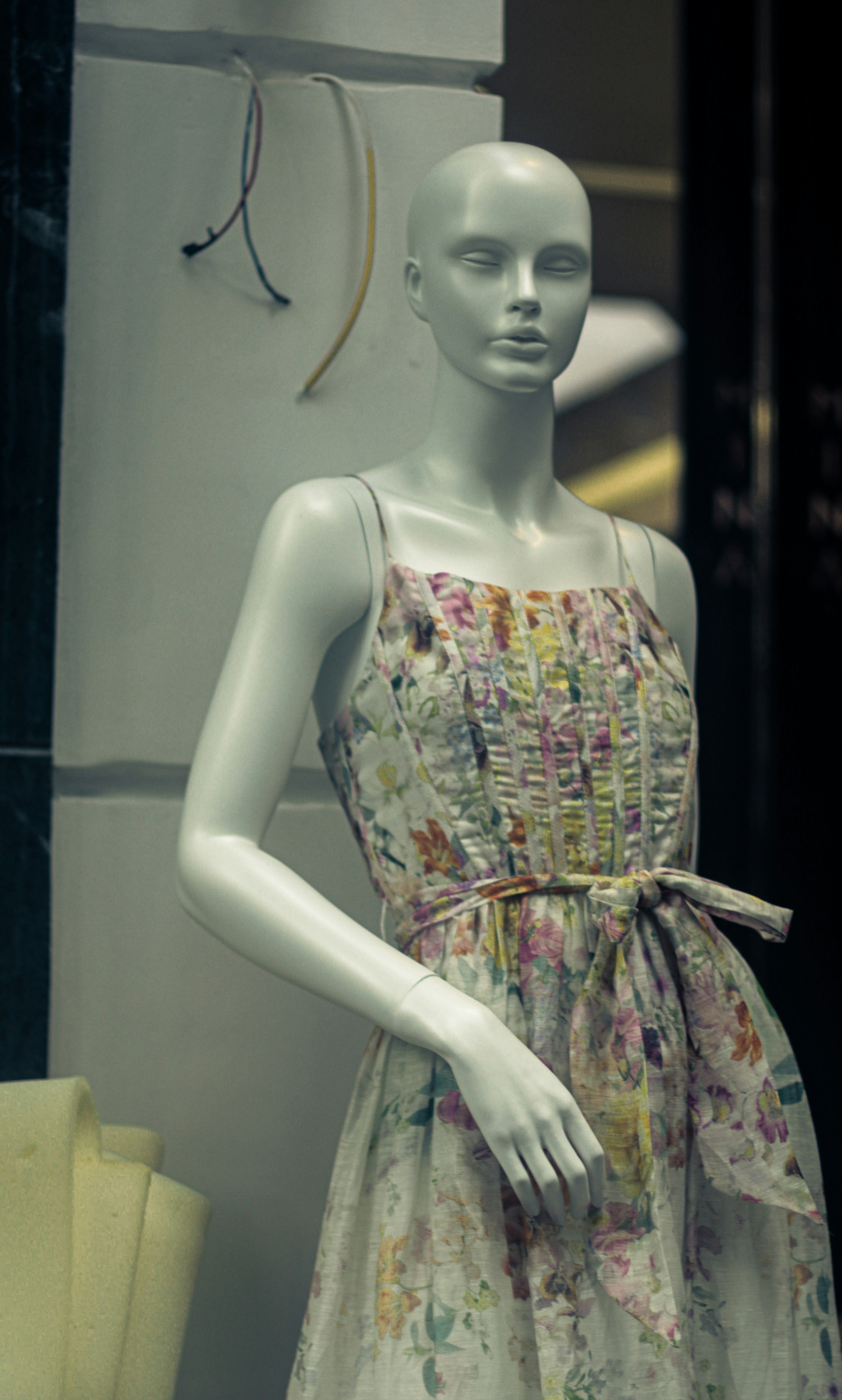 a white mannequin wearing a dress with flowers on it