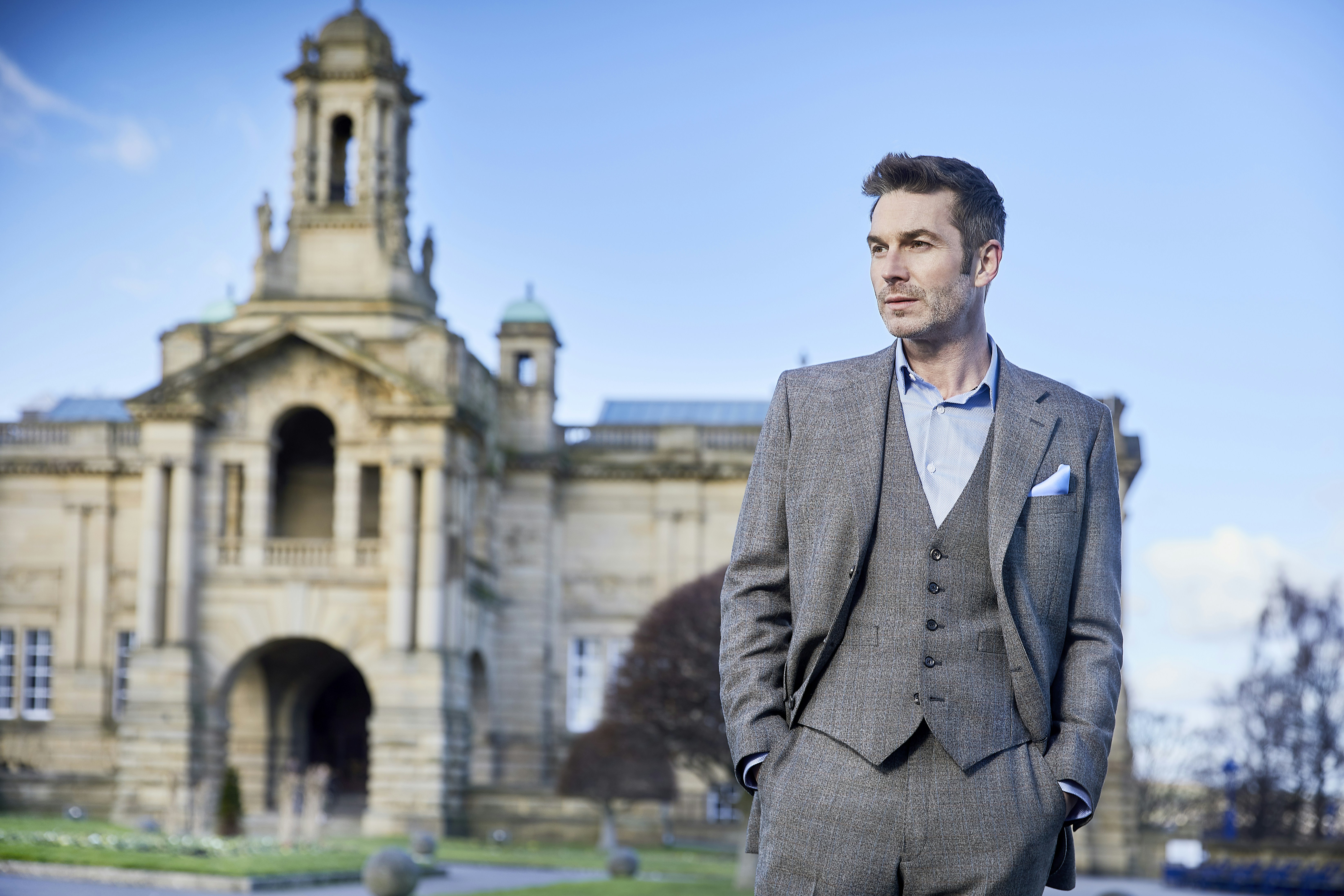 a man in a suit standing in front of a building