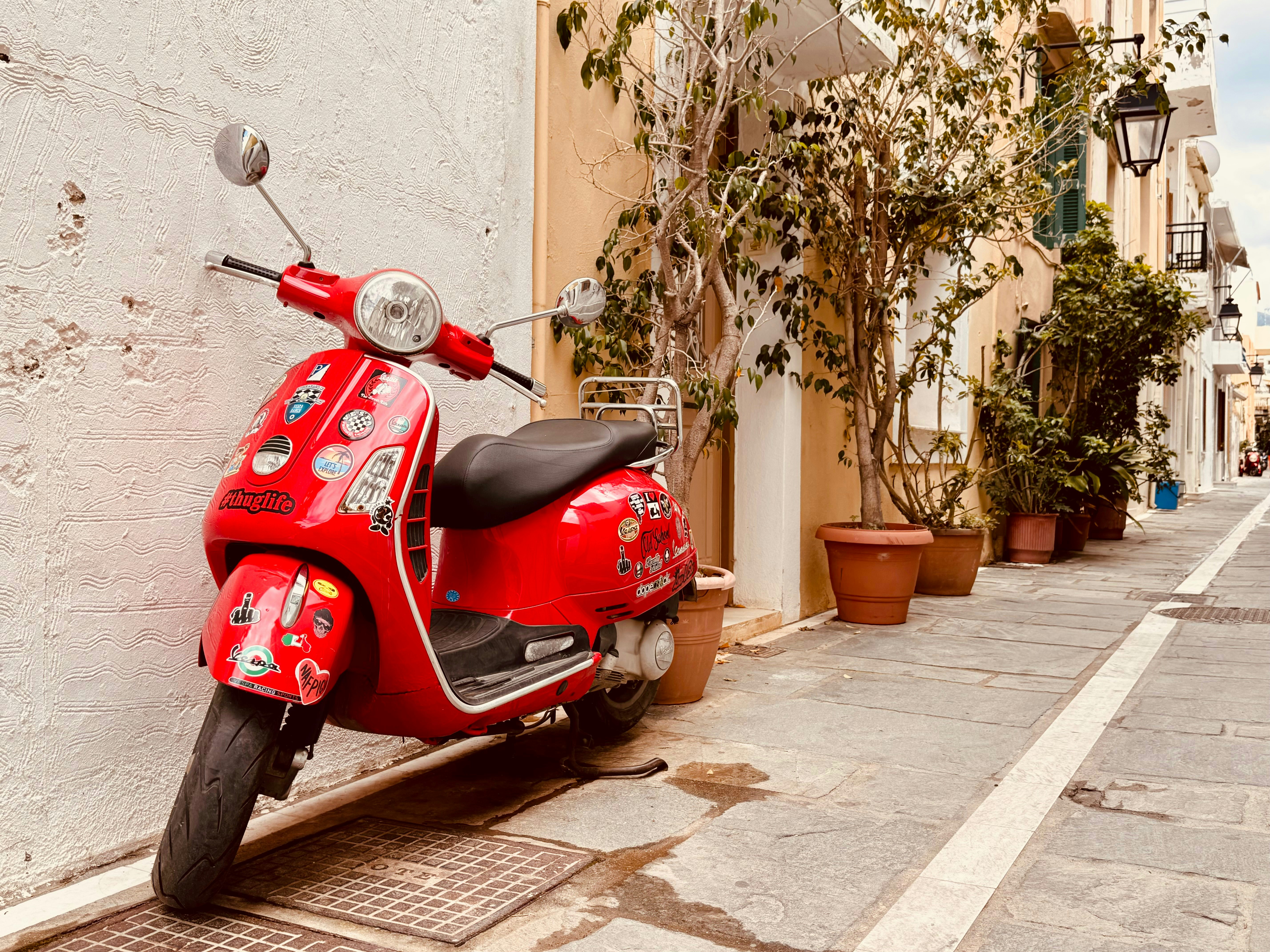A red scooter parked on the side of a street