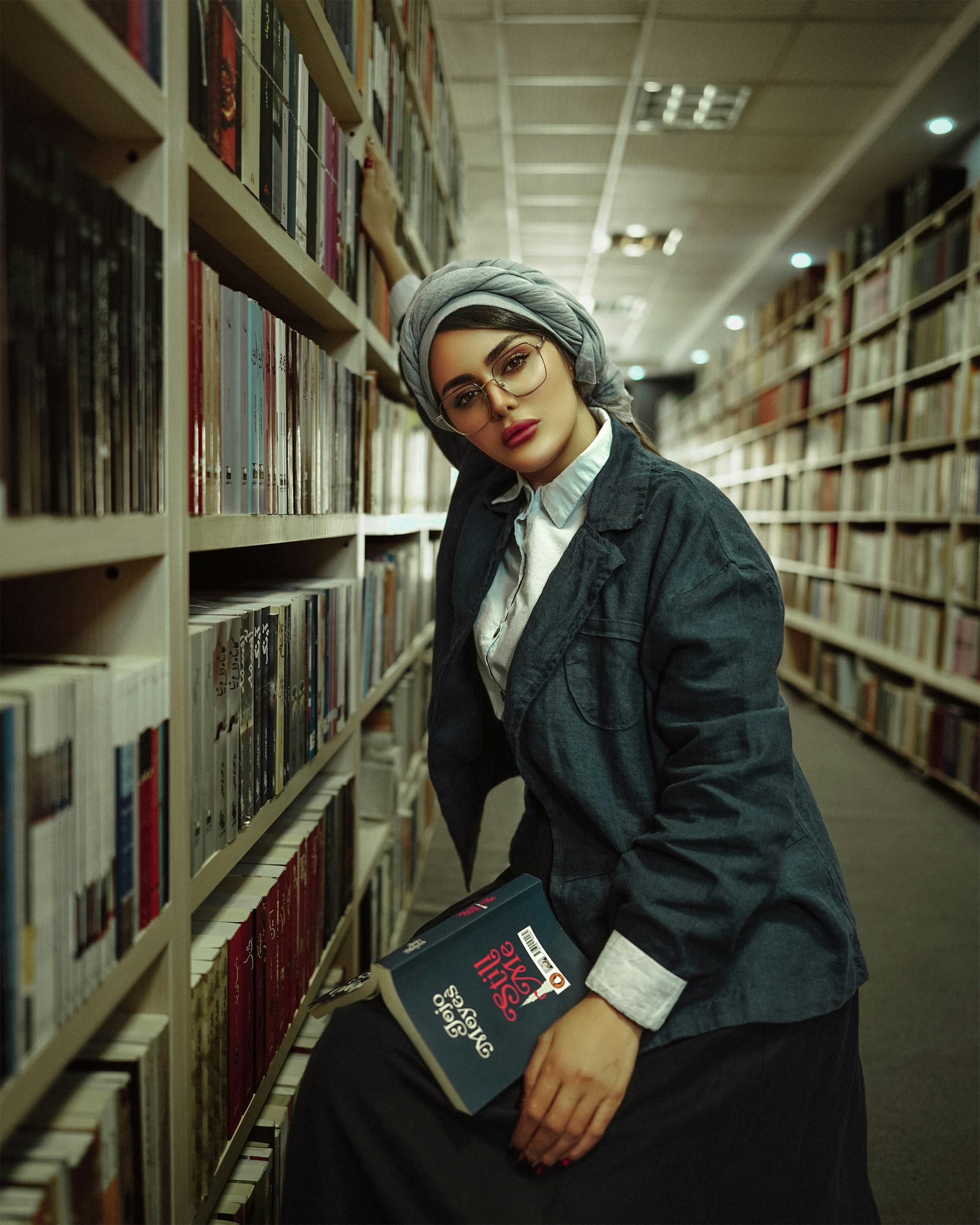 a woman sitting on a book shelf in a library