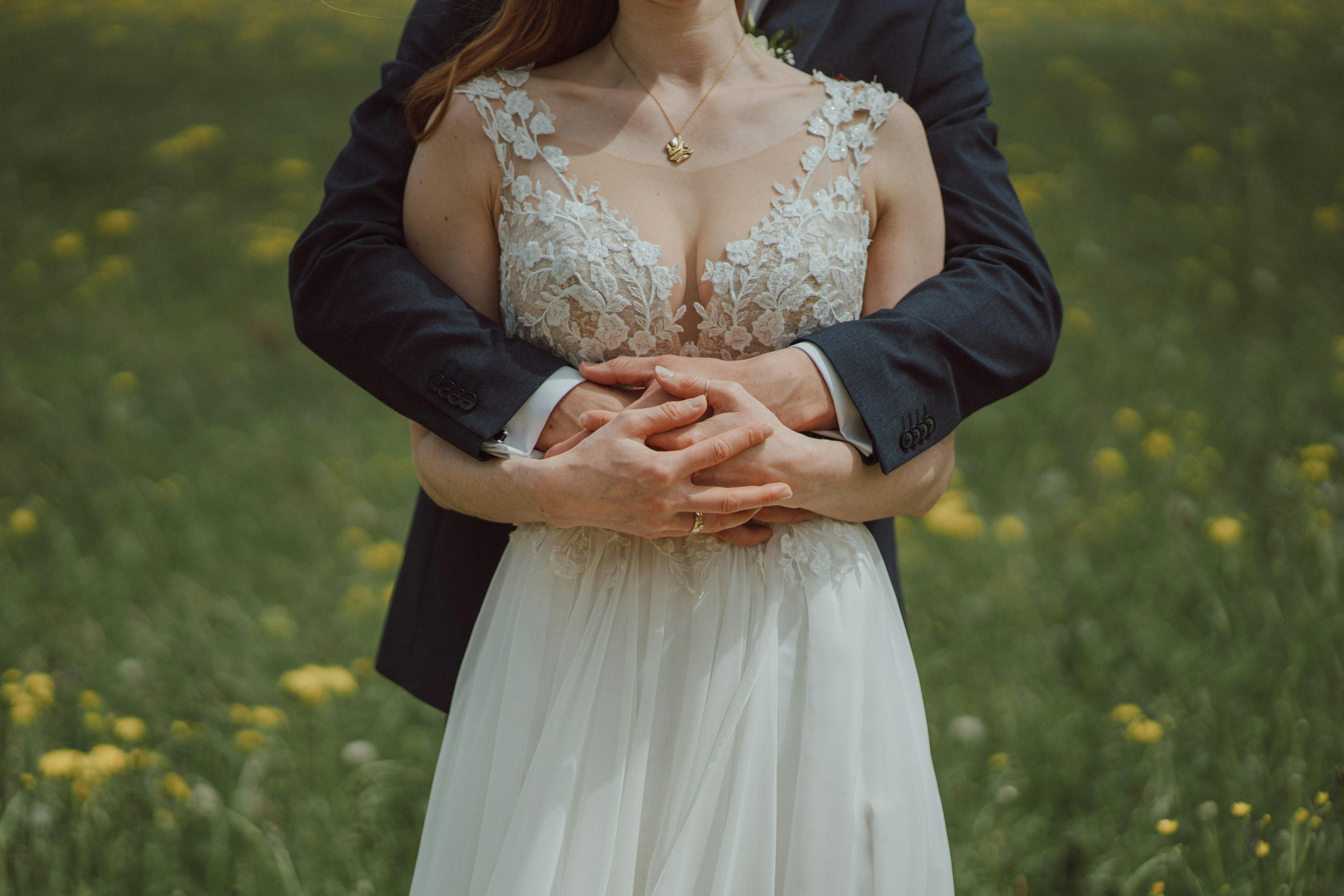 a bride and groom standing in a field of flowers