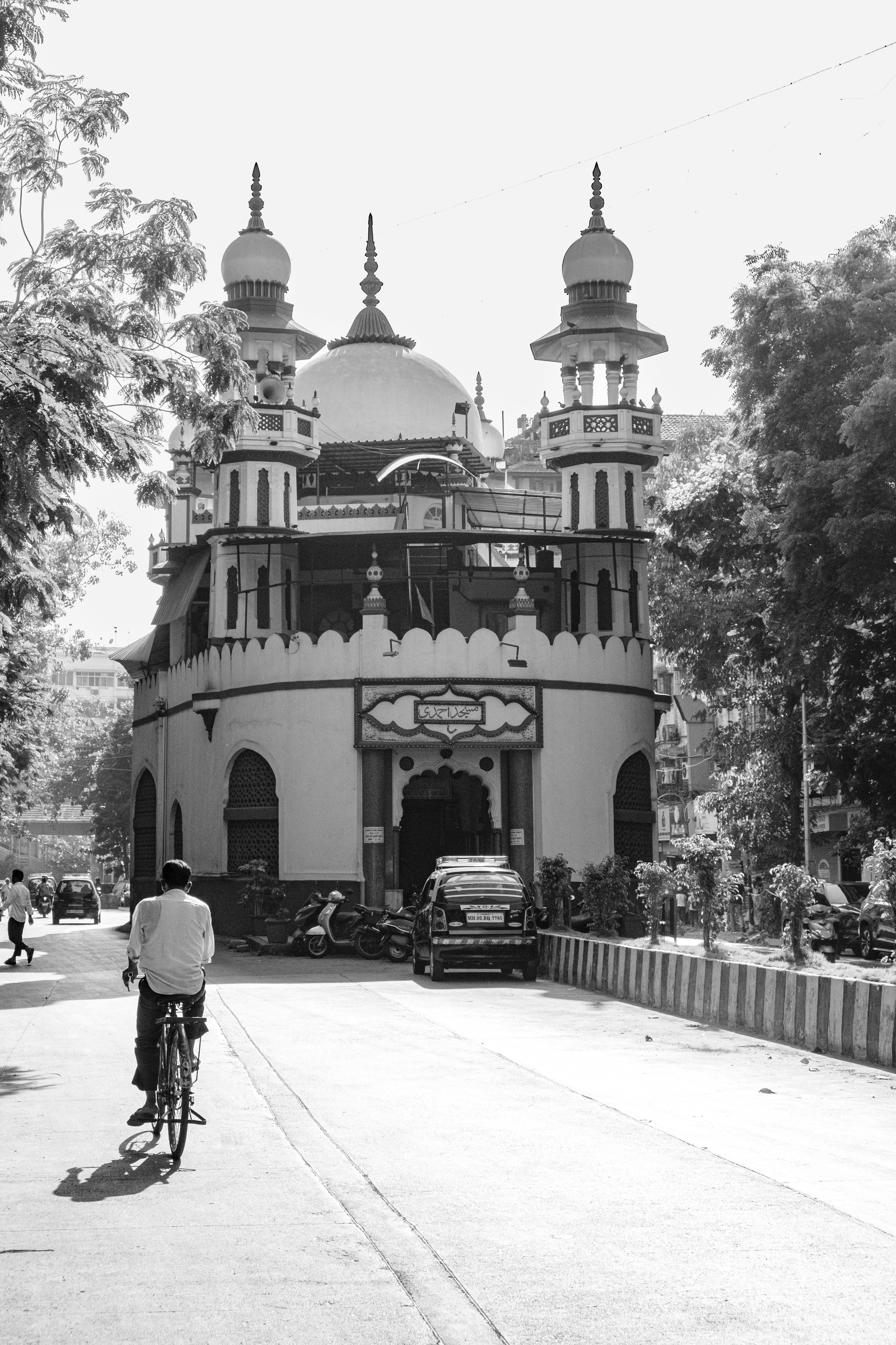 a black and white photo of a man riding a bike in front of a building