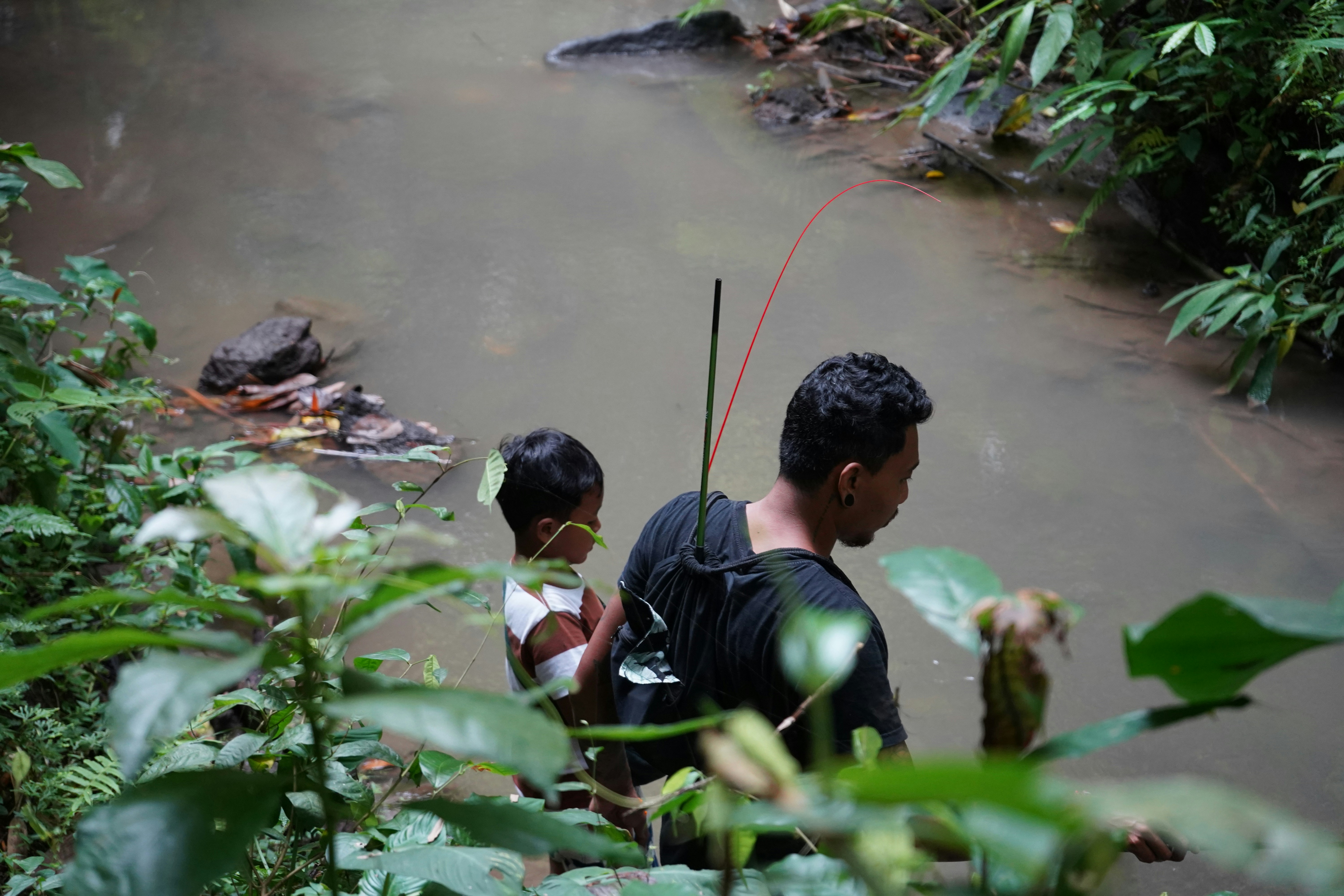 A serene moment of a father and son fishing in a tranquil stream