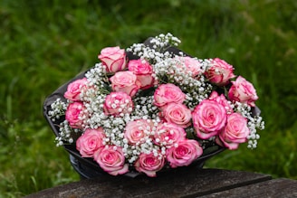 a bouquet of pink roses sitting on top of a wooden table