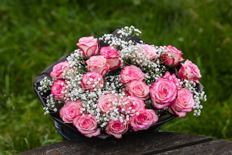 a bouquet of pink roses sitting on top of a wooden table