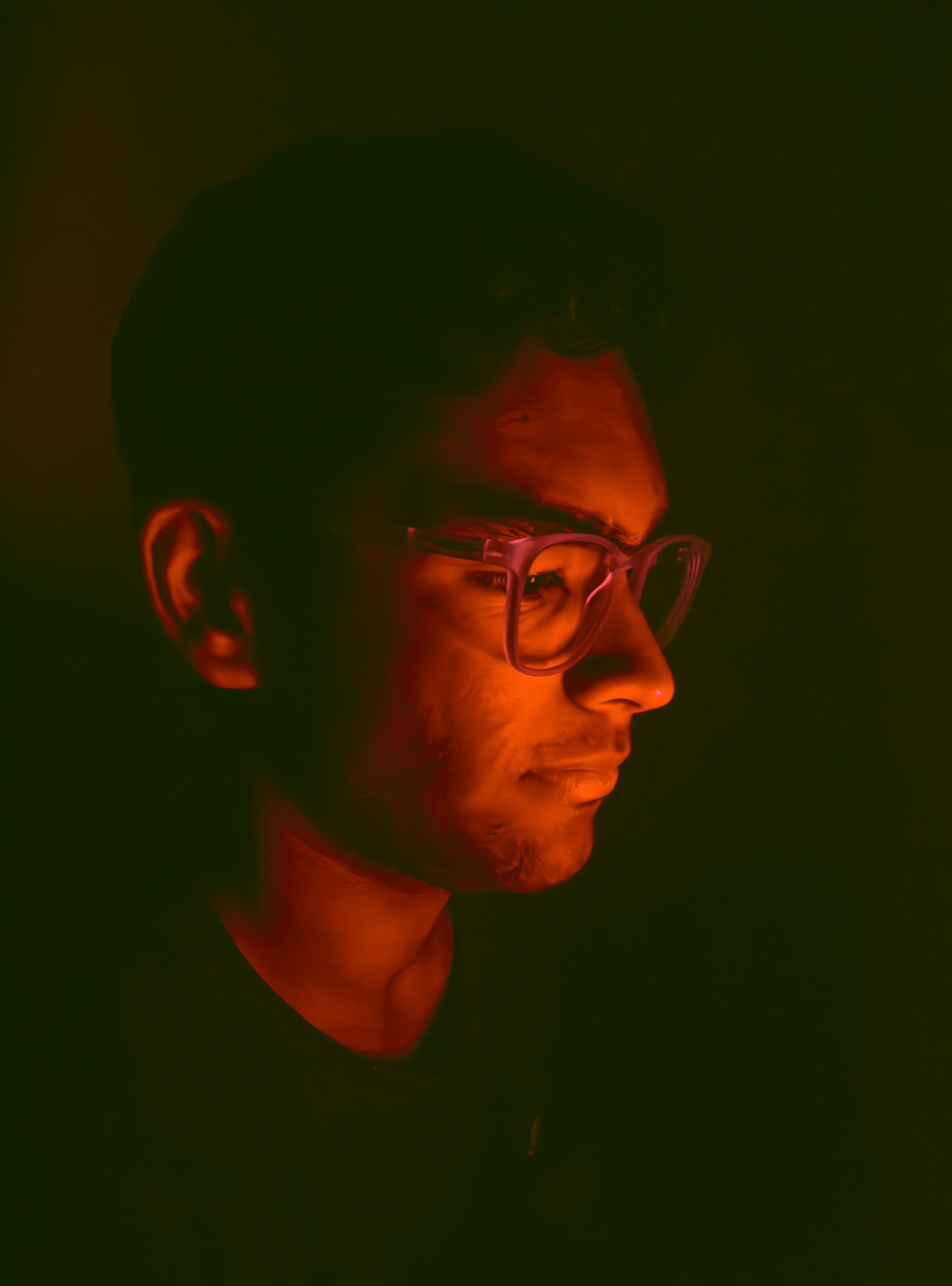 a man wearing glasses in a dark room