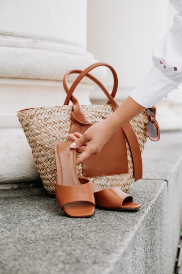 A woman's hand is holding a brown purse