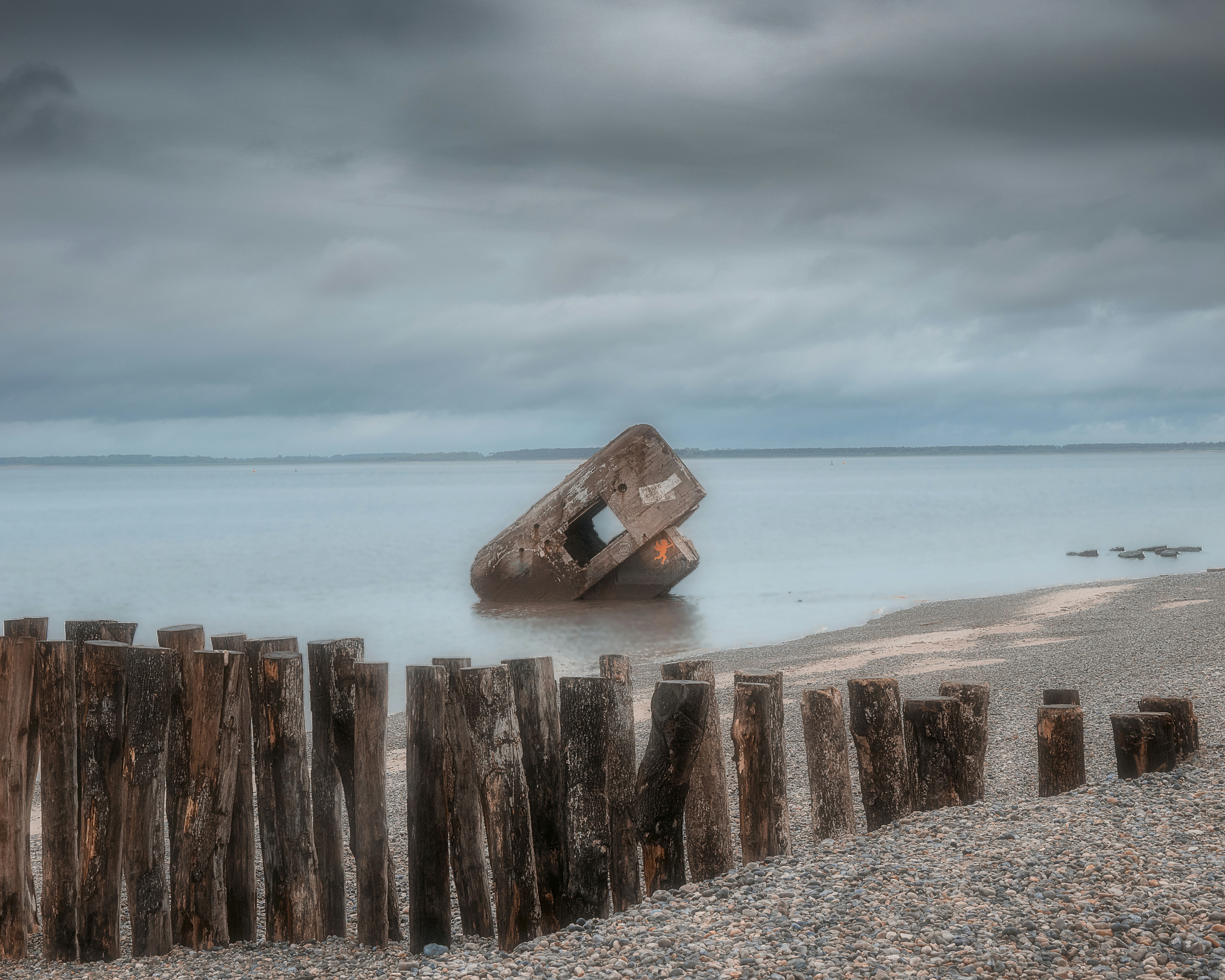 a boat sitting on top of a beach next to a wooden fence