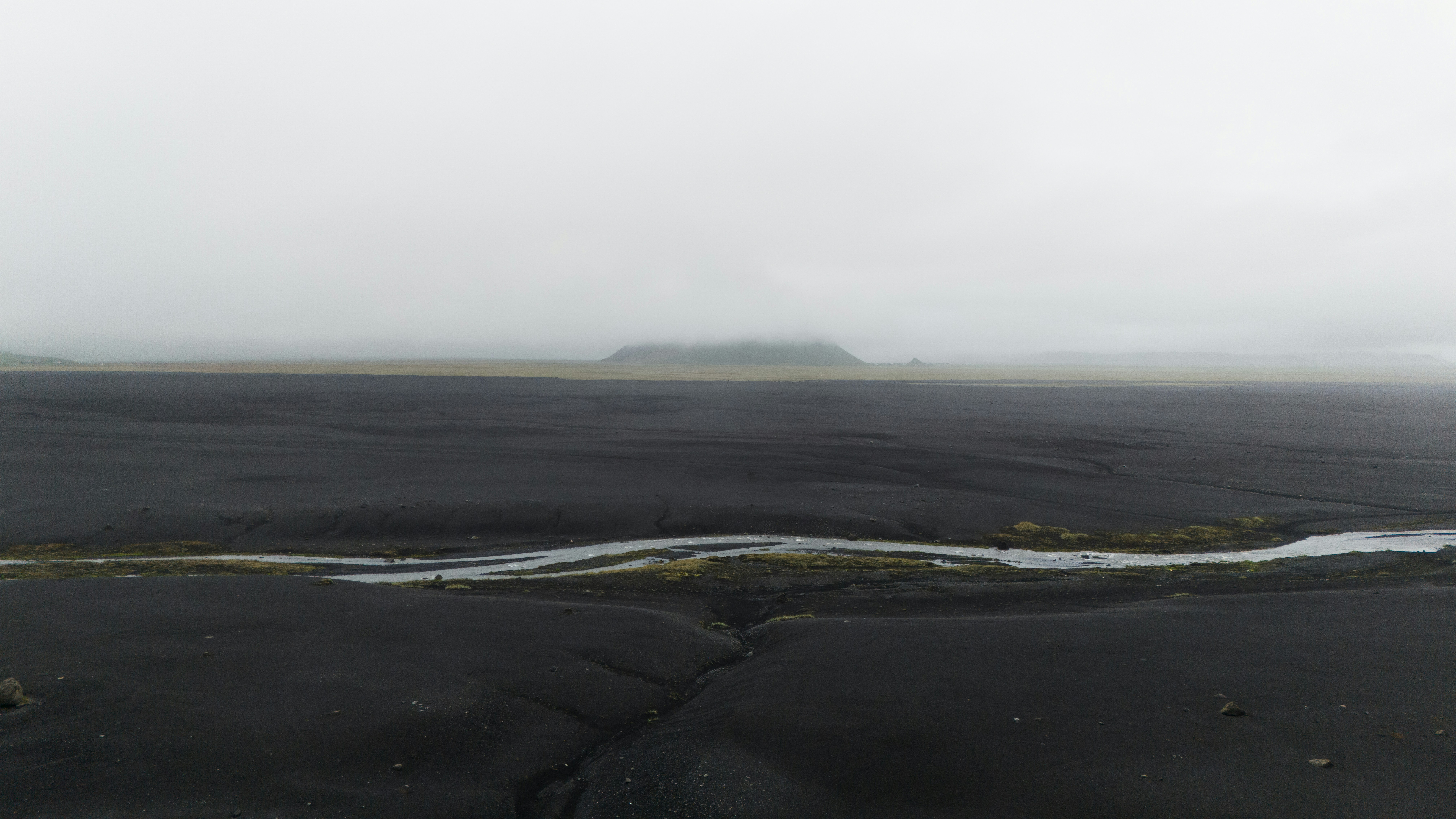 a river running through a barren landscape on a foggy day