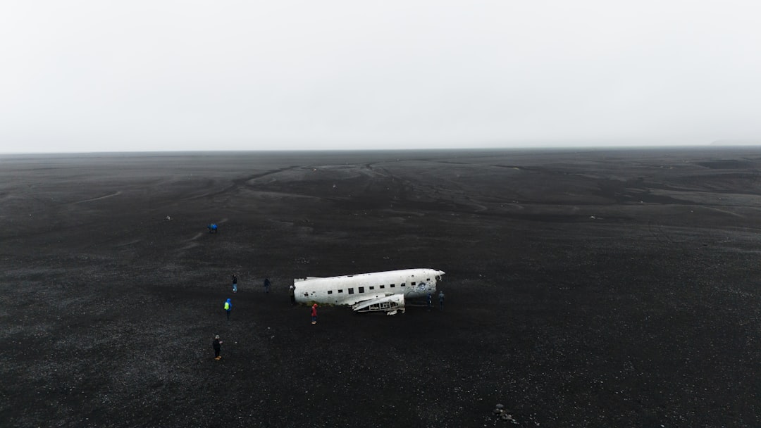 a small white airplane sitting on top of a black field,