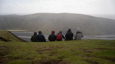 a group of people sitting on top of a lush green hillside